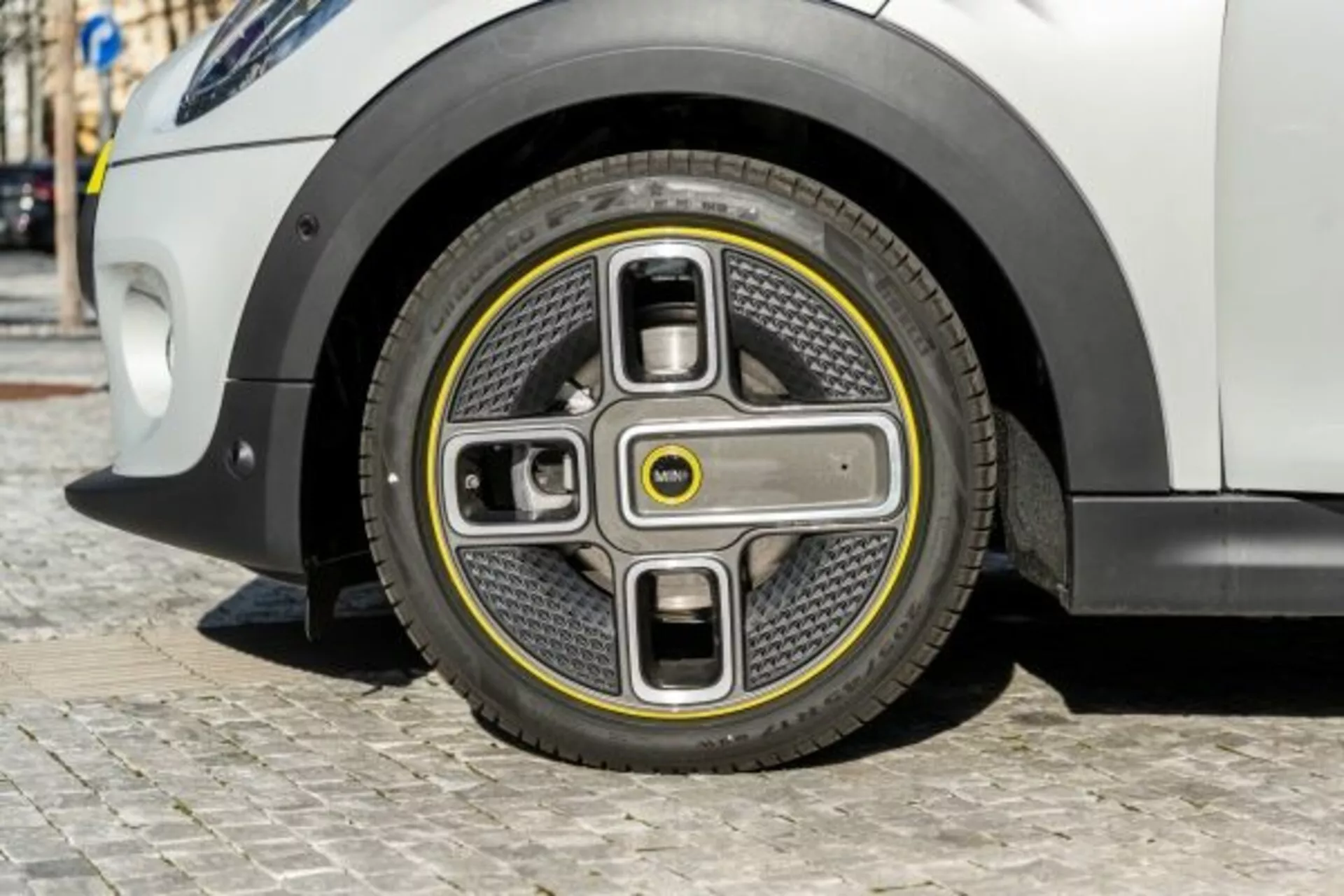Vista ravvicinata della ruota anteriore della Mini Mini 3 porte del 2018 con design futuristico bicolore e coprimozzo integrato, che suggerisce innovazioni nei veicoli elettrici e aerodinamica avanzata, su sfondo di carrozzeria bianca