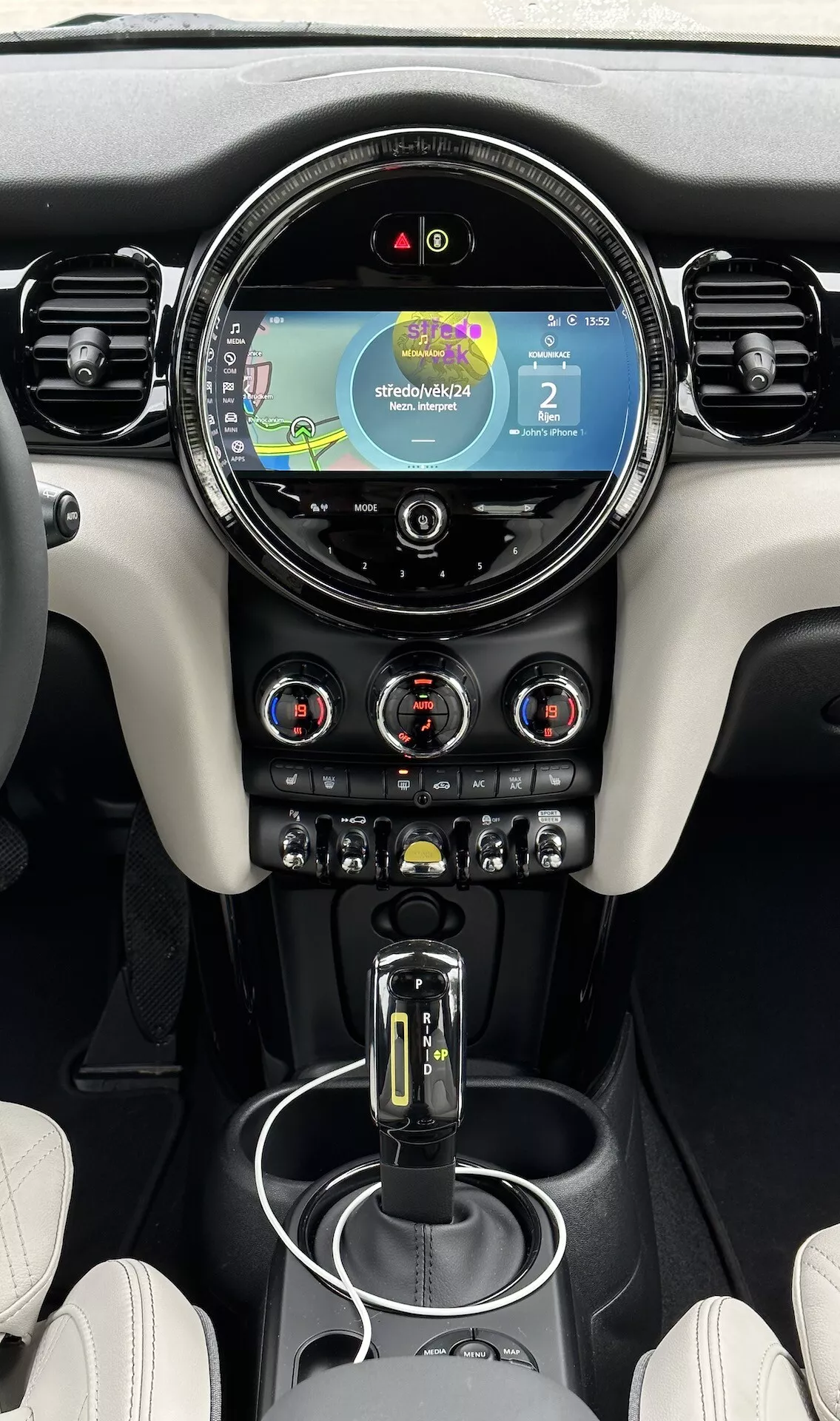 Vista interna di una Mini Electric 3 porte del 2021, con focus sulla console centrale e cruscotto dotato di display touch screen con navigazione, controllo clima bi-zona e selettore del cambio