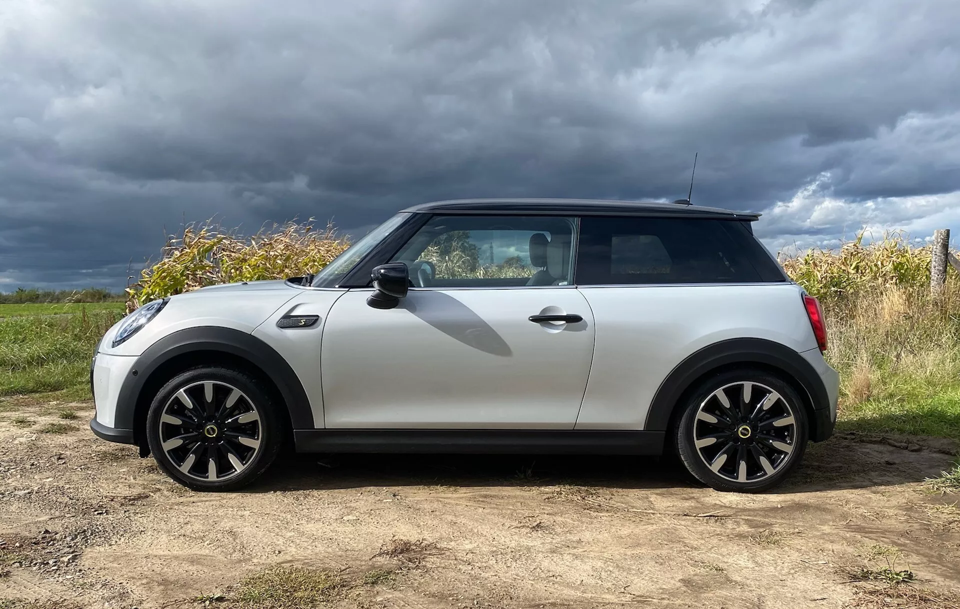 Mini Cooper Elettrica 3 Porte 2021 in Bianco e Nero, Dotata di Cerchi Sportivi e Sistema di Accesso Senza Chiave, su uno Sfondo di Cielo Coperto e Paesaggio Naturale