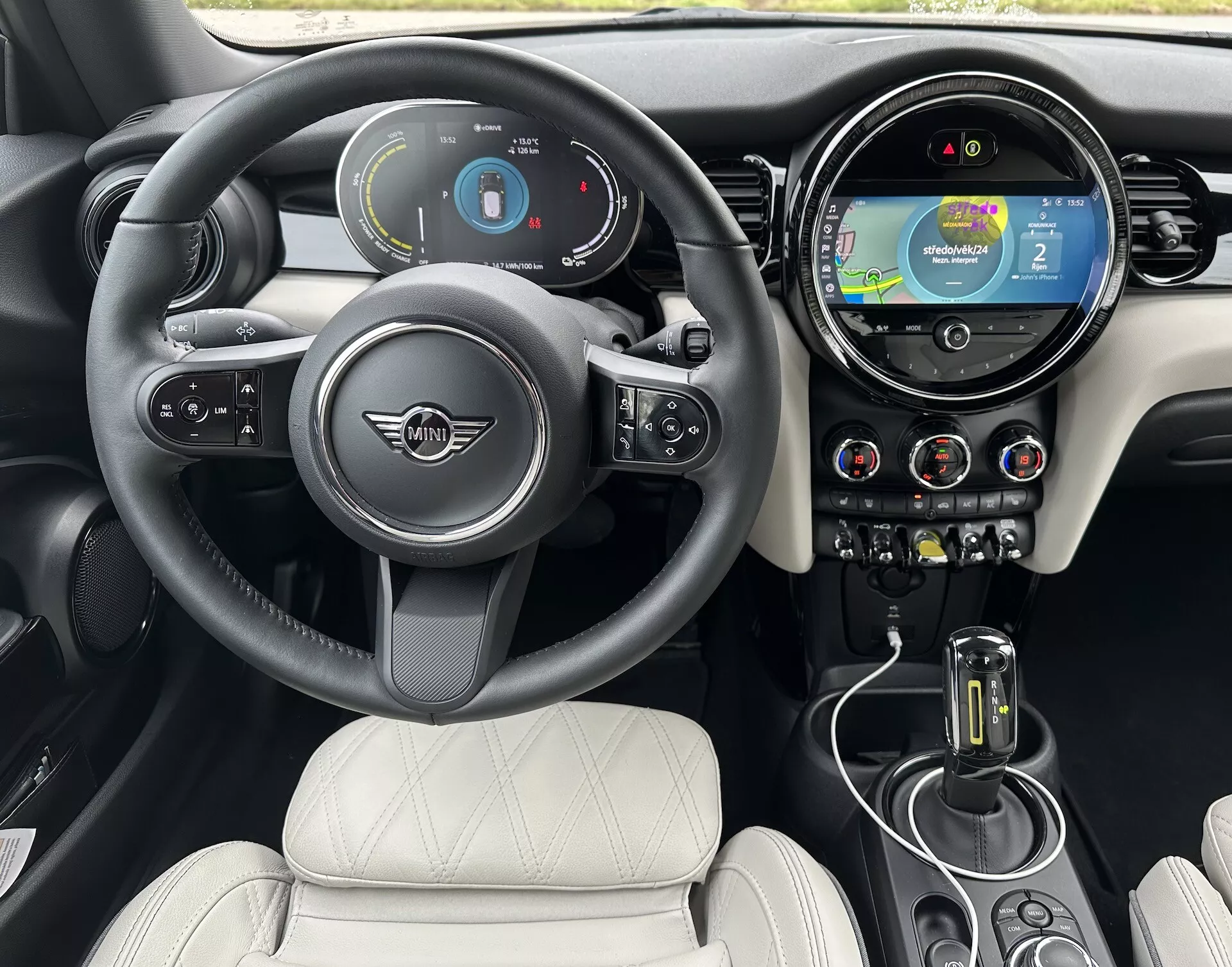 Interno della Mini Elettrica 3 Porte 2021 con volante con logo e controlli, cruscotto digitale, sistema di infotainment touch con navigazione, controlli climatici a bilanciere, leva del cambio automatico e sedili in pelle trapuntata