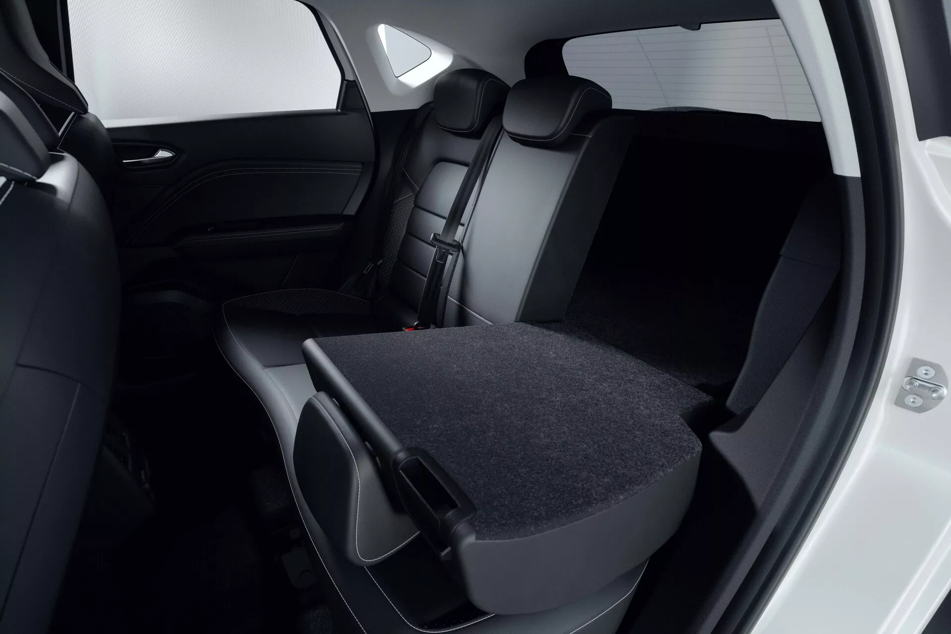 Vista ravvicinata dell'interno del passeggero posteriore della Mitsubishi ASX 2023 (2ª generazione). Concentrazione sui sedili rivestiti in pelle o similpelle scura, dove il sedile posteriore destro è abbassato, mostrando la flessibilità del carico. La porta posteriore è aperta, rivelando un interno scuro abbinato e finestre oscurate. Il design moderno e minimalista è evidente nella palette di colori nero o grigio scuro. L'immagine mette in risalto la capacità di stivaggio del veicolo e l'impegno per la sicurezza con poggiatesta e cinture di sicurezza visibili.