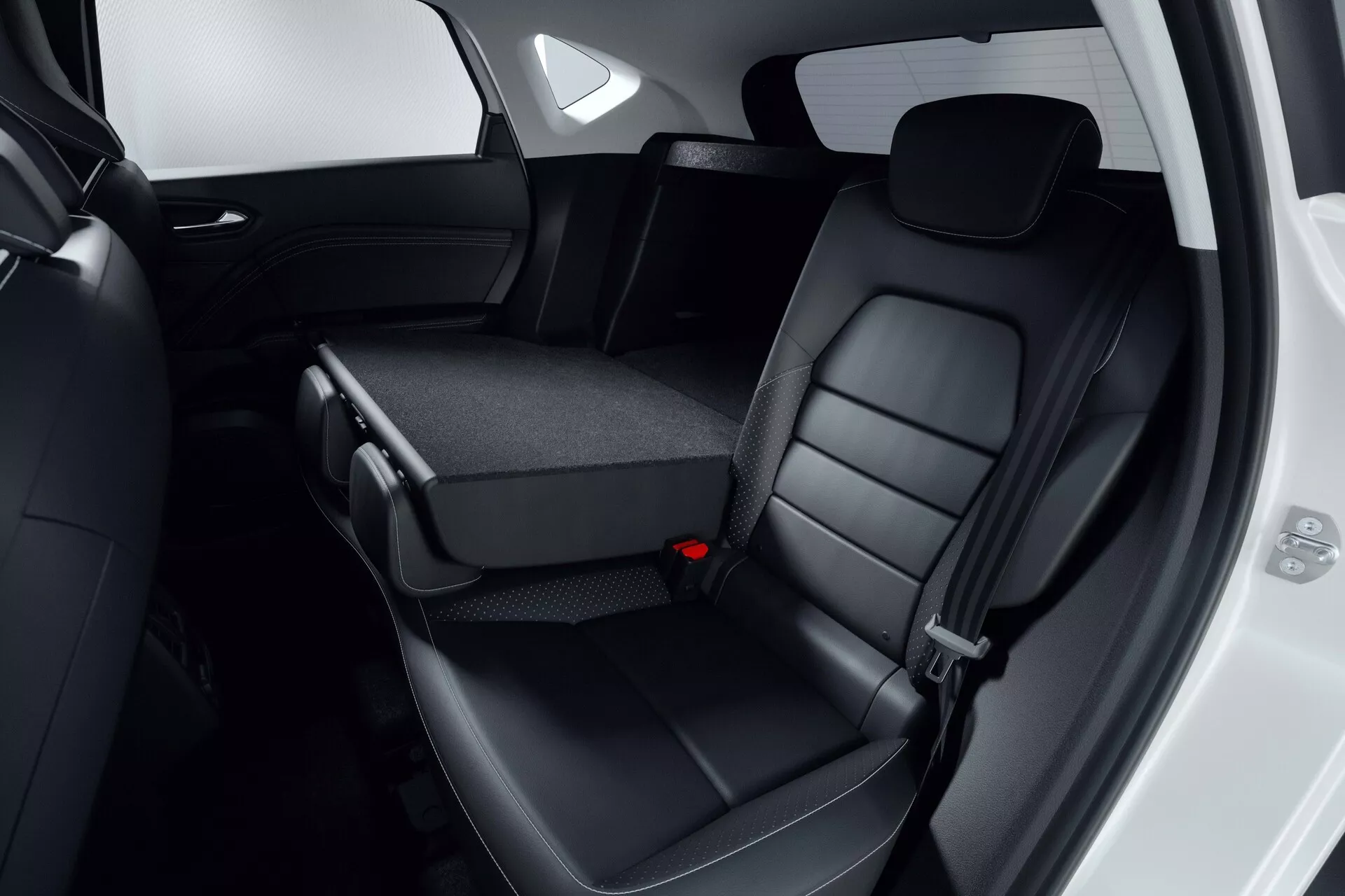 Vista interna dell'area dei sedili posteriori della Mitsubishi ASX 2023 (2ª generazione), con sedili posteriori rivestiti in pelle nera con poggiatesta e cuciture dettagliate. Il sedile centrale parzialmente ripiegato rivela portabicchieri o area di stivaggio, evidenziando il design pieghevole 60/40. Il bordo della porta del passeggero è aperto, mostrando elementi di design del pannello porta dell'auto. L'immagine si concentra sul comfort, la qualità dei materiali e le caratteristiche di convenienza, rispettando i moderni standard di sicurezza, inclusi i cinture di sicurezza a tre punti.