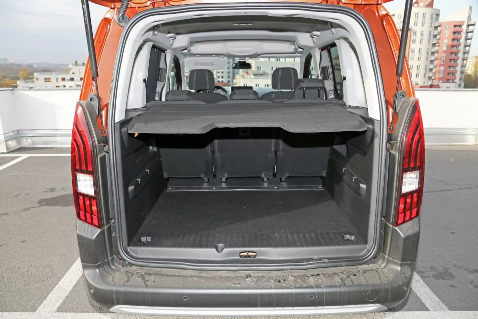 Vista posteriore di un SUV Peugeot 3008 del 2016 con focus sul bagagliaio aperto e l'area di carico, presentando un pavimento piatto e pulito con un tappetino protettivo, una copertura del carico parzialmente estesa, sedili posteriori ribaltabili, e visibilità chiara dell'area dei sedili anteriori attraverso la parte posteriore.