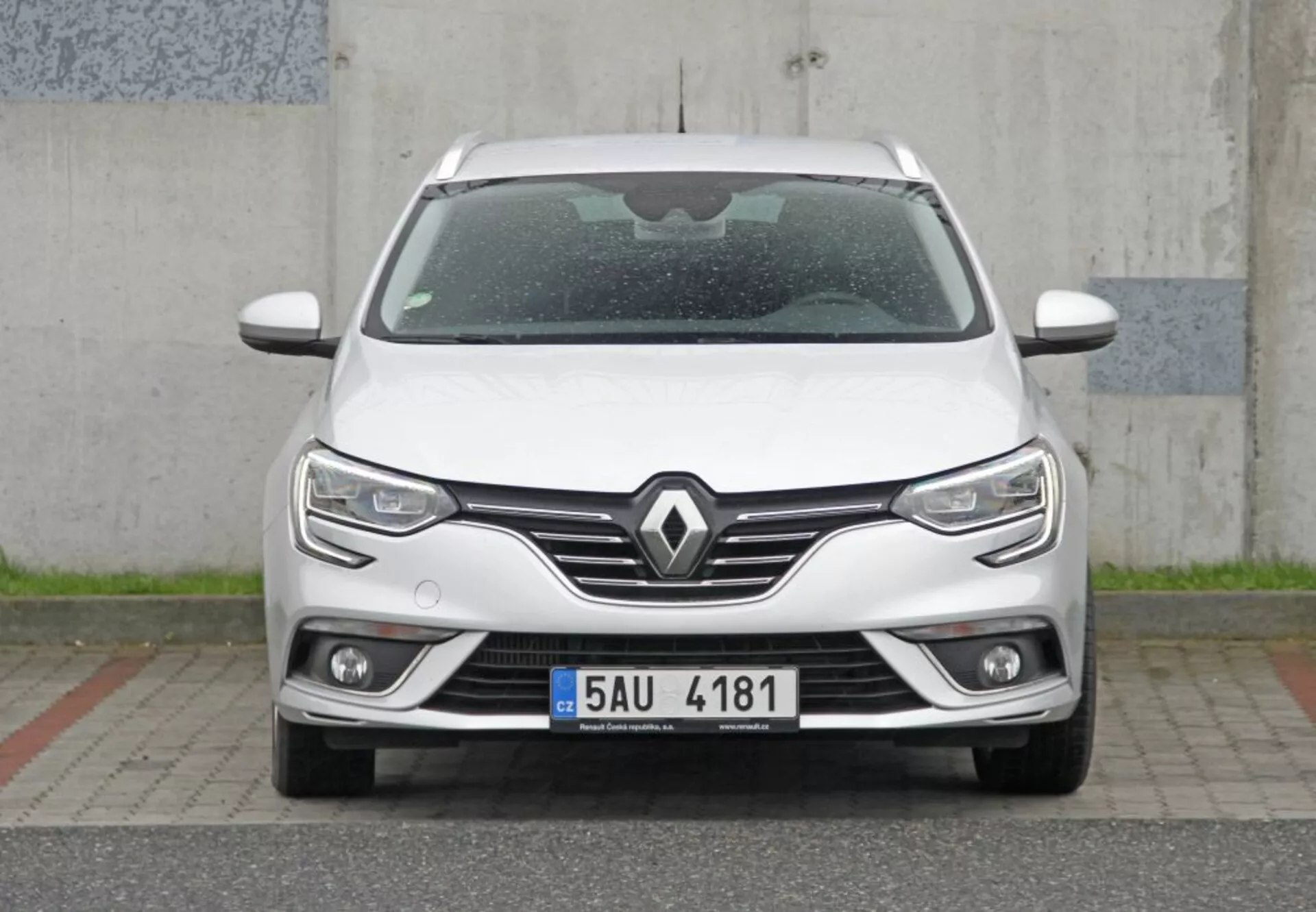 Vista frontale diretta di una elegante Peugeot 308 SW 2013 bianca con griglia prominente con emblema Renault, fari LED moderni con luci diurne, fari fendinebbia integrati e tecnologia dei sensori di parcheggio, enfatizzando un design moderno e aerodinamico.