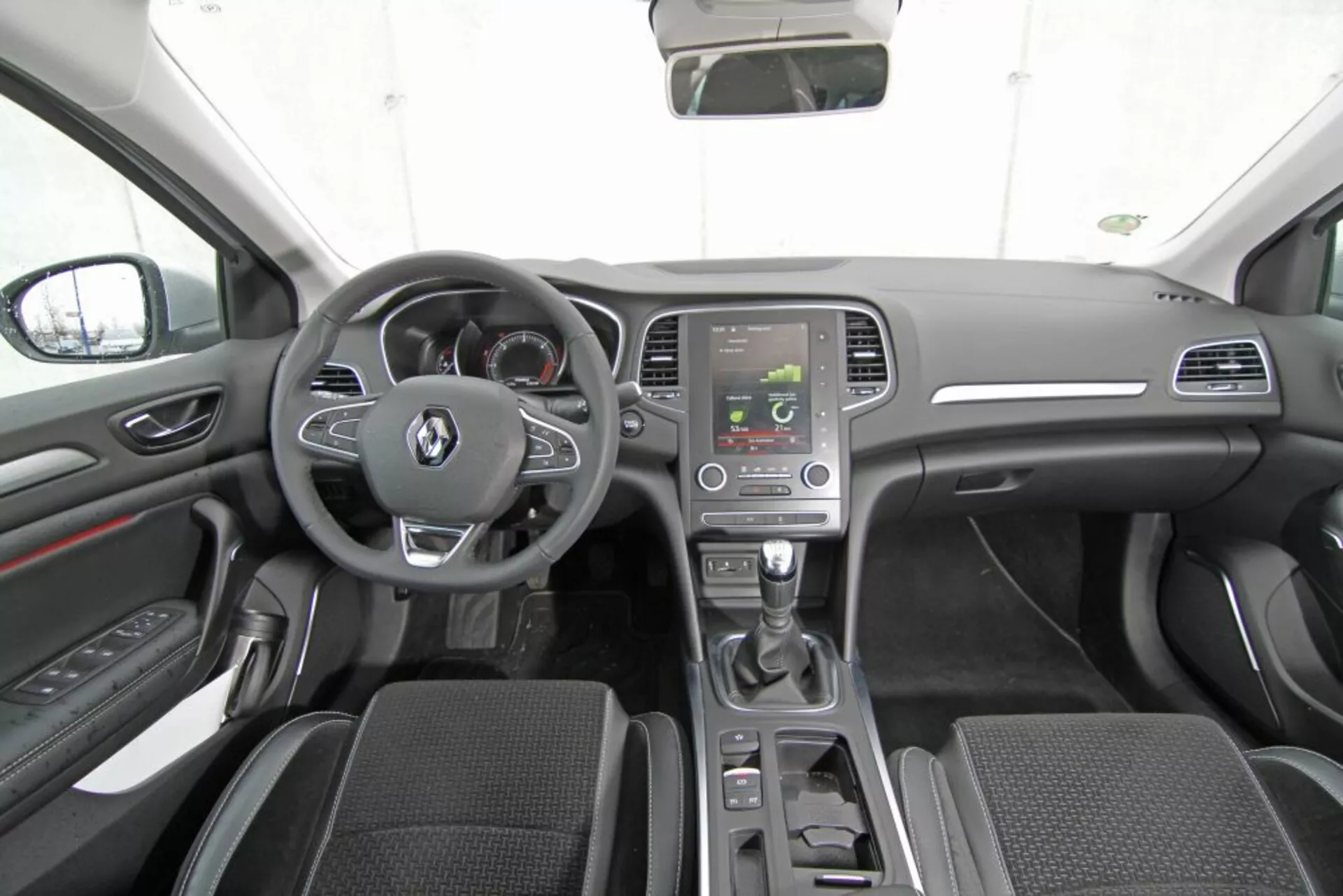 Vista interna della Peugeot 308 SW 2013 dal sedile posteriore centrale mostrando cruscotto, volante con pulsanti multifunzione, cluster strumenti, console centrale con schermo infotainment, leva del cambio automatico, controlli del clima, sedili anteriori in tessuto, pannelli porta con controlli, specchietti laterali, tetto dell'auto, specchietto retrovisore, e schema di colori scuri moderno con accenti argento