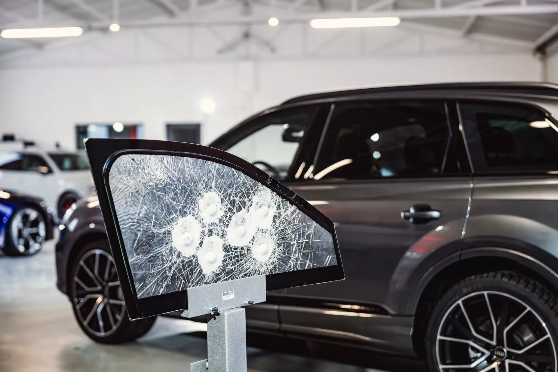 Peugeot 308 2022 esposta in concessionaria con focus su display di vetro frantumato che ricorda lo specchio laterale in primo piano, suggerendo funzionalità di sicurezza o test di durabilità, e presentando il profilo laterale elegante dell'auto con caratteristiche moderne di SUV sullo sfondo