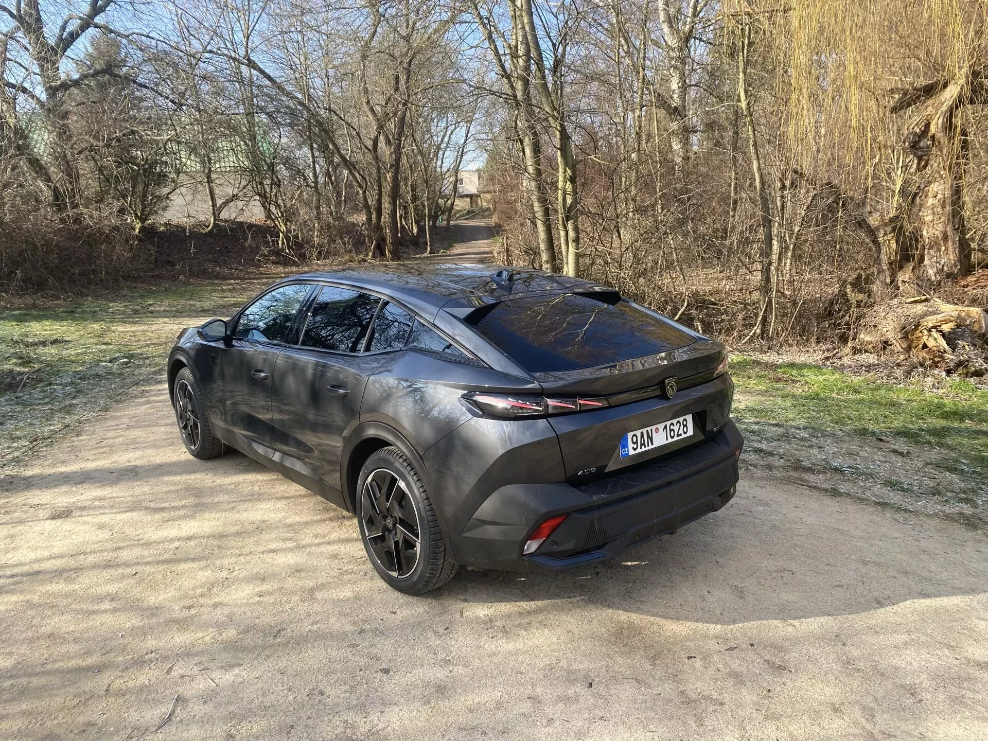 Vista posteriore tre quarti del Peugeot 408 2023 che mette in mostra il suo design moderno da crossover, evidenziando il portellone, l'elegante lunotto posteriore e i fanali orizzontali estesi sul lato carrozzeria, con uno scorcio di cerchi in lega, profilo laterale scolpito e verniciatura bicolore alla luce naturale del sole