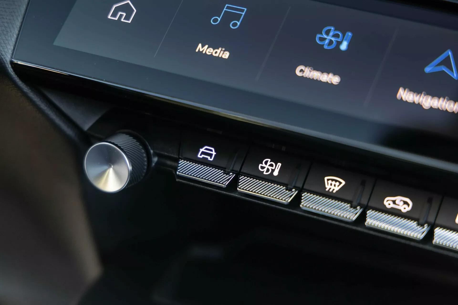 Interfaccia di controllo centrale della Peugeot 408 2023 che mostra pulsanti tattili illuminati e parte del display touchscreen con icone di infotainment e controllo del clima, mostrando la tecnologia avanzata del veicolo