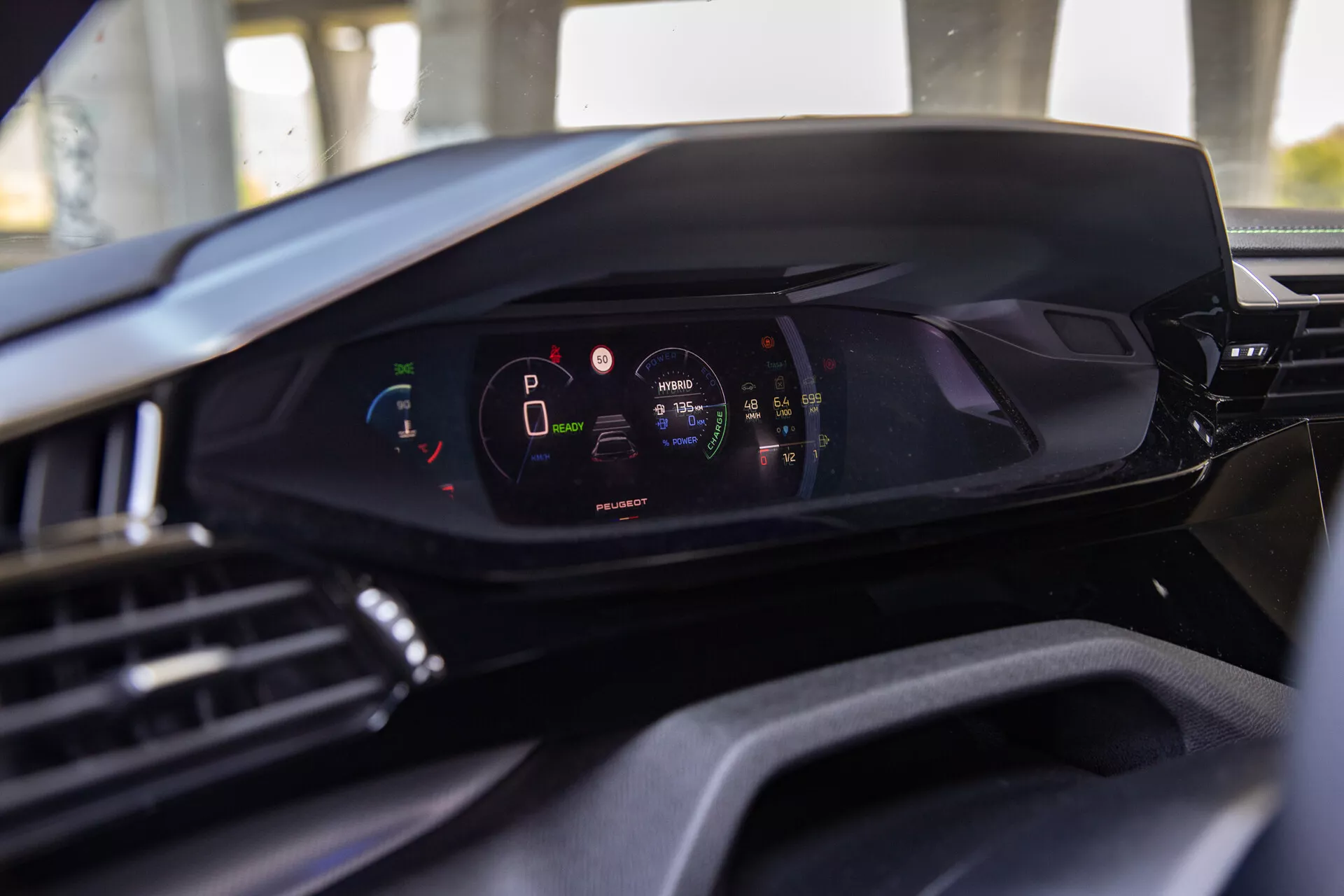 Vista interna della Peugeot 408 2023 che mostra la moderna plancia digitale dalla prospettiva del sedile del conducente, evidenziando il quadro strumenti digitale con il veicolo in modalità parcheggio e alto livello di carica della batteria
