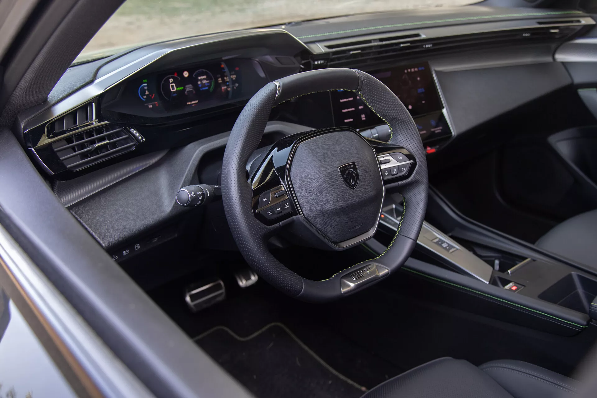 Interno della Peugeot 408 2023 che mostra un volante multifunzione in pelle, cruscotto digitale e sistema di infotainment touchscreen dal punto di vista del lato del conducente