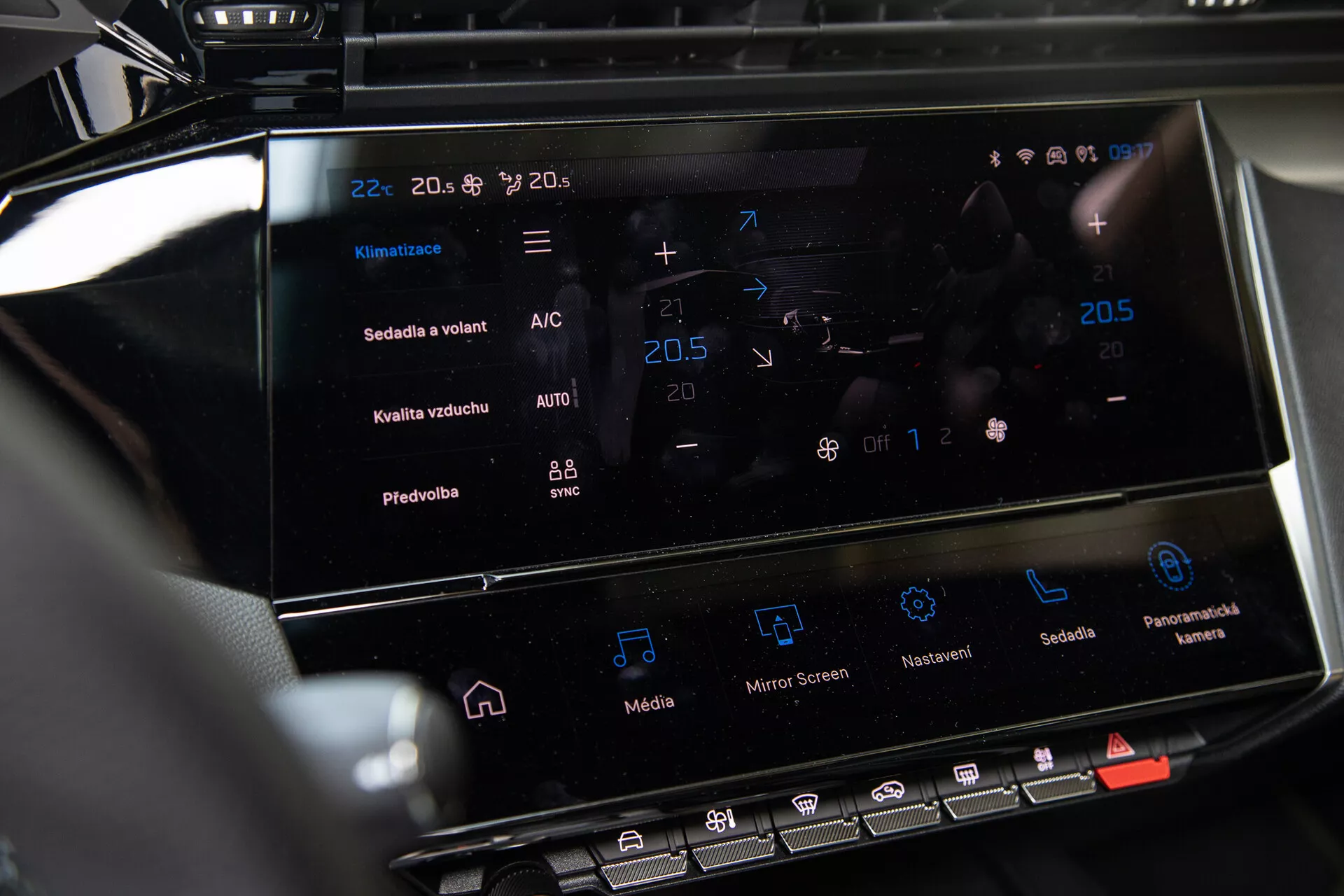 Console centrale della Peugeot 408 2023 che mostra il sistema di infotainment touchscreen e l'interfaccia di controllo clima con impostazioni di temperatura e funzionalità avanzate