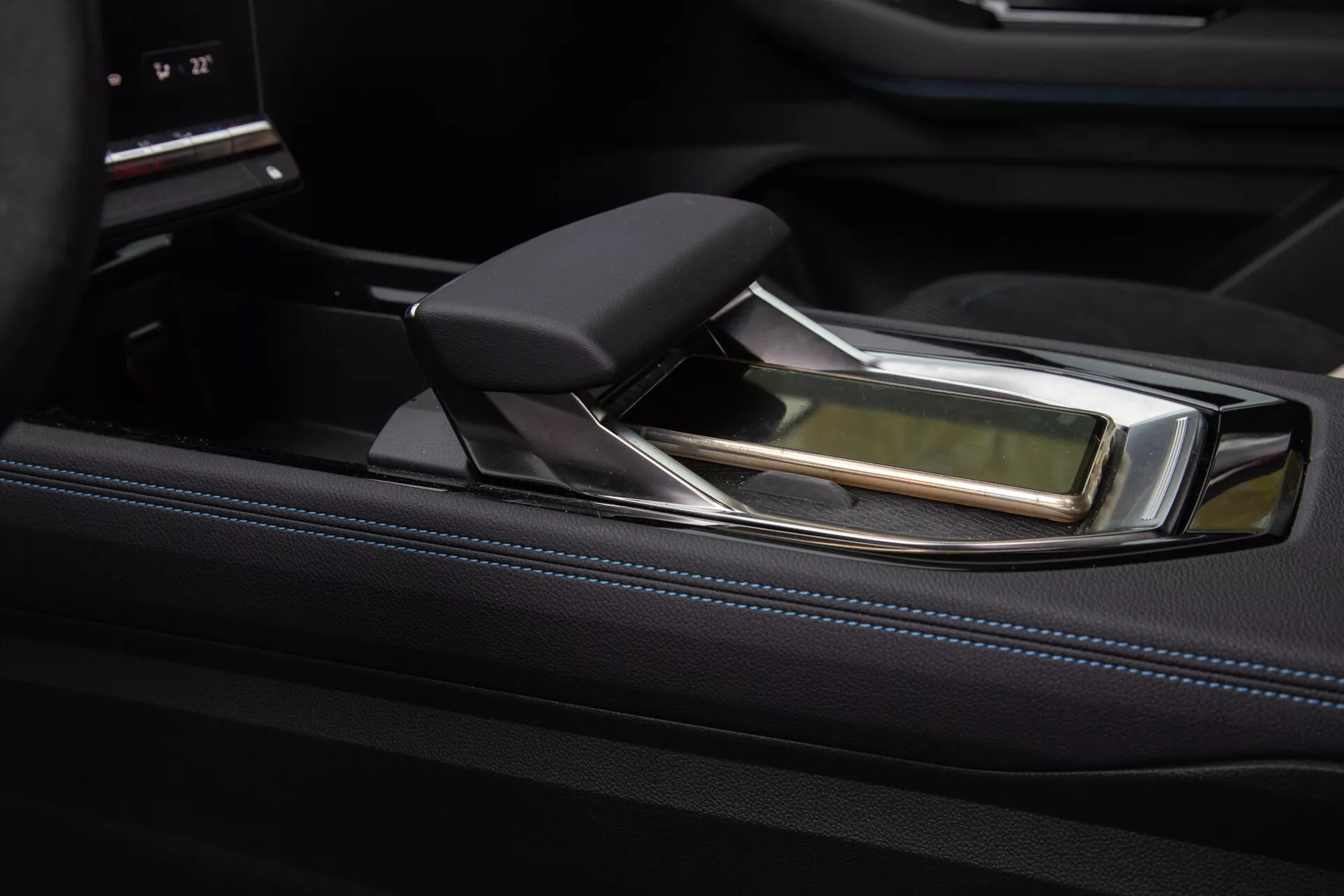 Vista ravvicinata della console centrale lussuosa della Renault Austral 2022 con una leva del cambio automatico moderna, caratterizzata da un design ergonomico con accenti in pelle e cromo, impostata su un rivestimento nero lucido e un interfaccia di controllo dell'infotainment sofisticato.