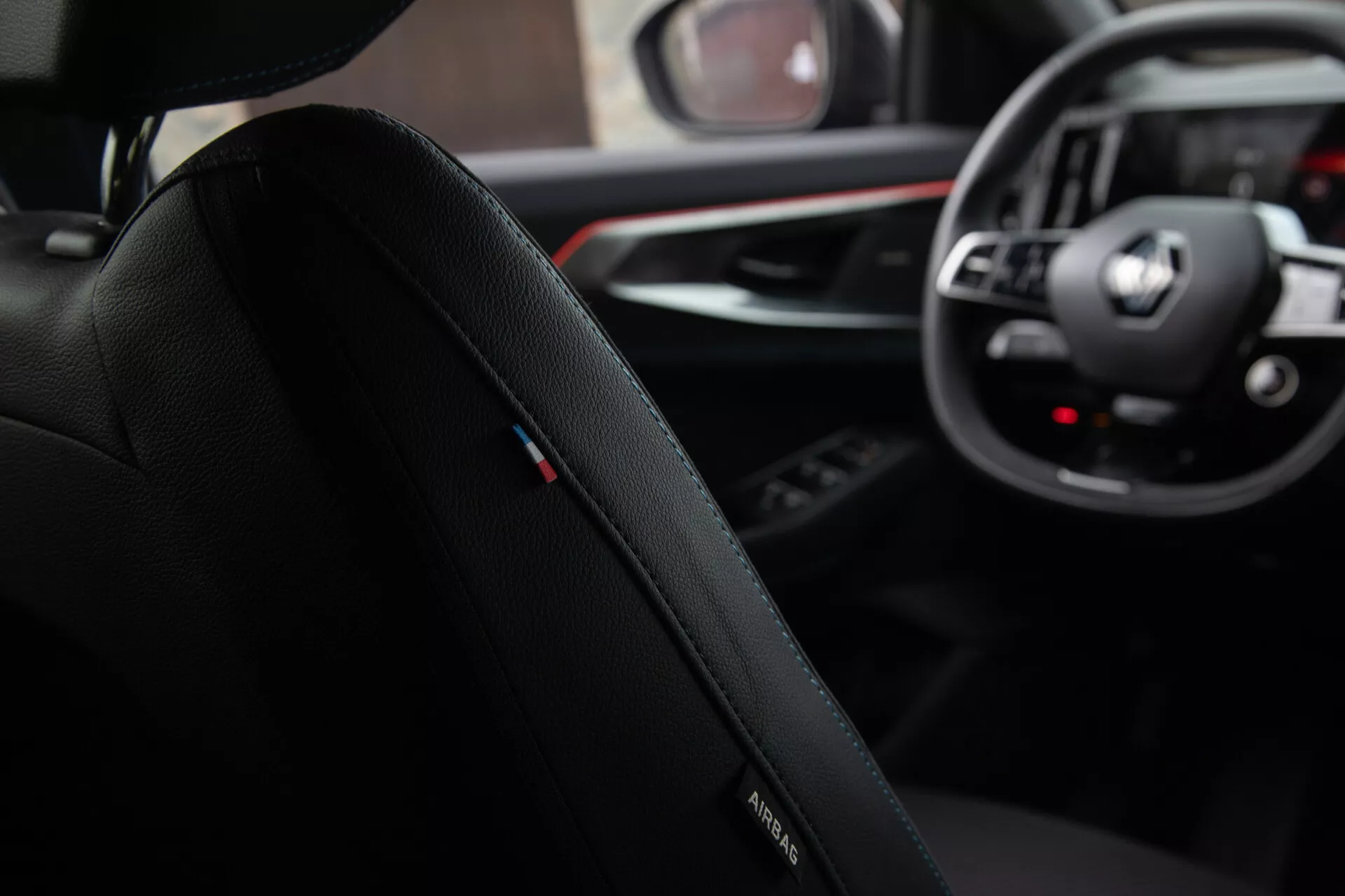 Vista interna dal punto di vista del passeggero posteriore che presenta il sedile del conducente con logo BMW, tappezzeria in pelle premium e cuciture dettagliate, concentrata verso il cruscotto con emblema BMW sul volante, quadranti analogici e display digitali del sistema di infotainment, insieme a uno scorcio della leva del cambio e del pannello di controllo multimediale in un design della cabina sofisticato ed ergonomico.