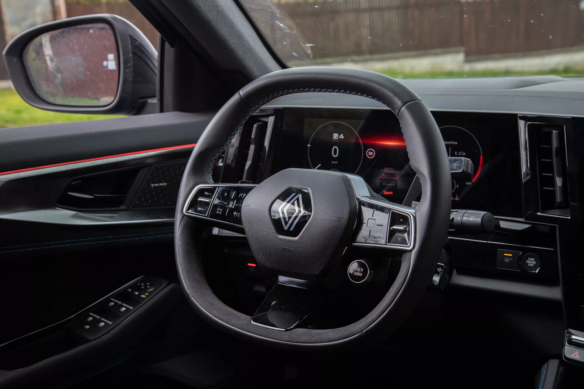 Scatto dell'interno di Renault Austral 2022 dalla prospettiva del guidatore che mostra il volante con comandi integrati, quadro strumenti digitale e parte della console centrale.