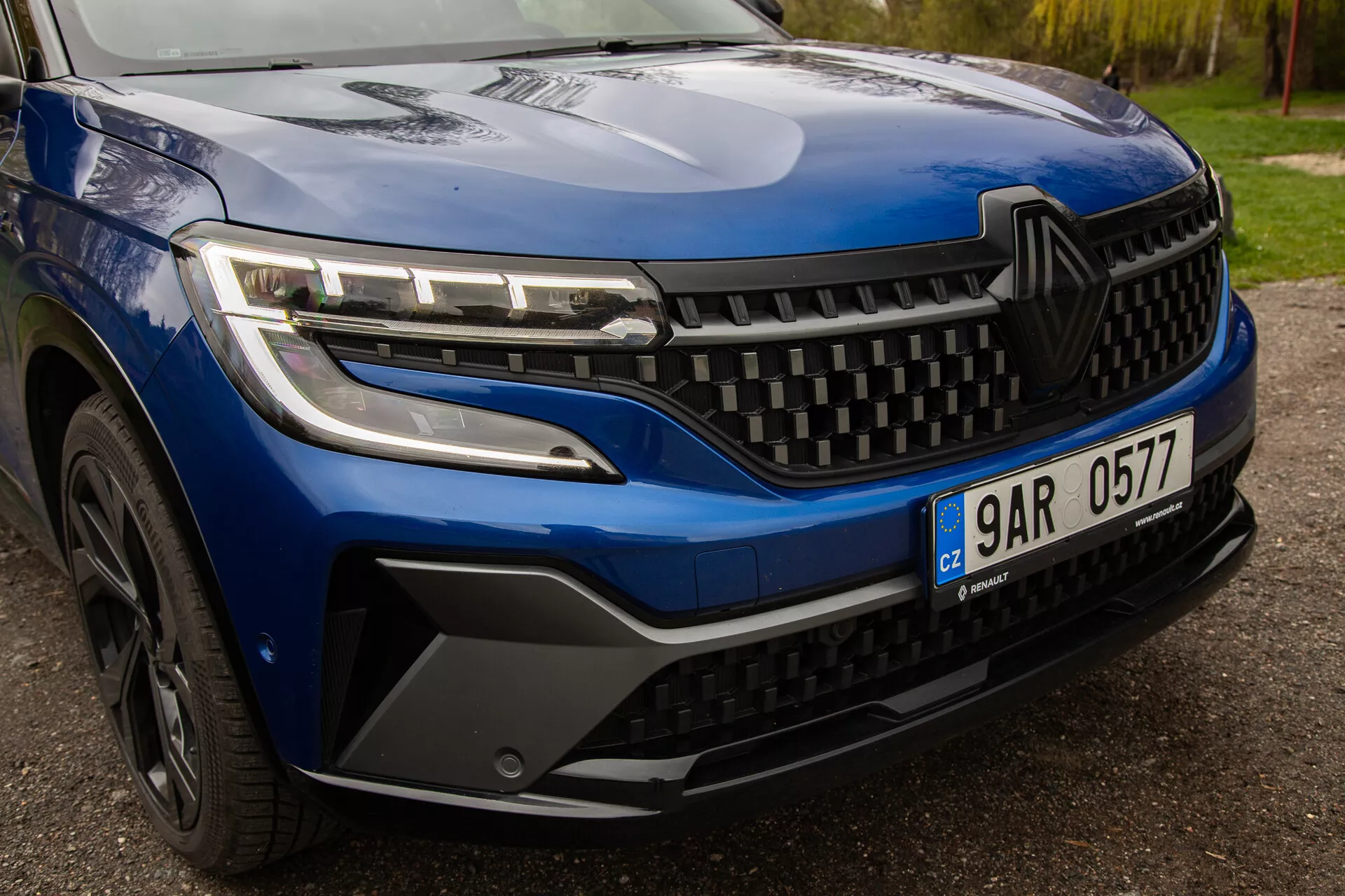 Vista ravvicinata della Renault Austral 2022, che mette in mostra fari LED eleganti, un design della griglia dinamico e stile dettagliato del paraurti anteriore e della ruota, enfatizzando l'estetica e la tecnologia del veicolo moderno.
