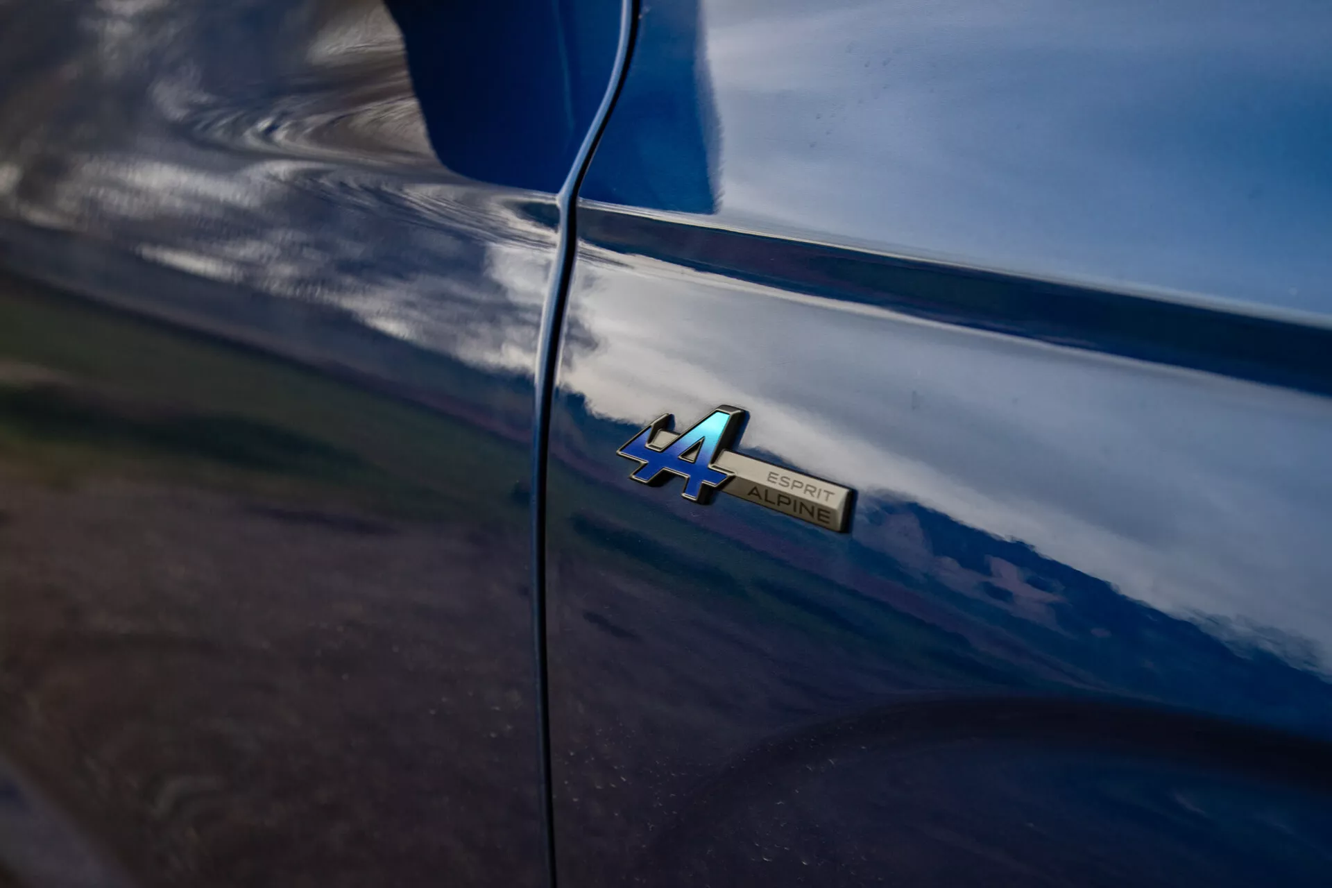 Dettaglio ravvicinato del badge '4A' del Renault Austral 2022 su carrozzeria lucida con riflessi naturali e linee morbide che suggeriscono manutenzione di alta qualità e ambiente