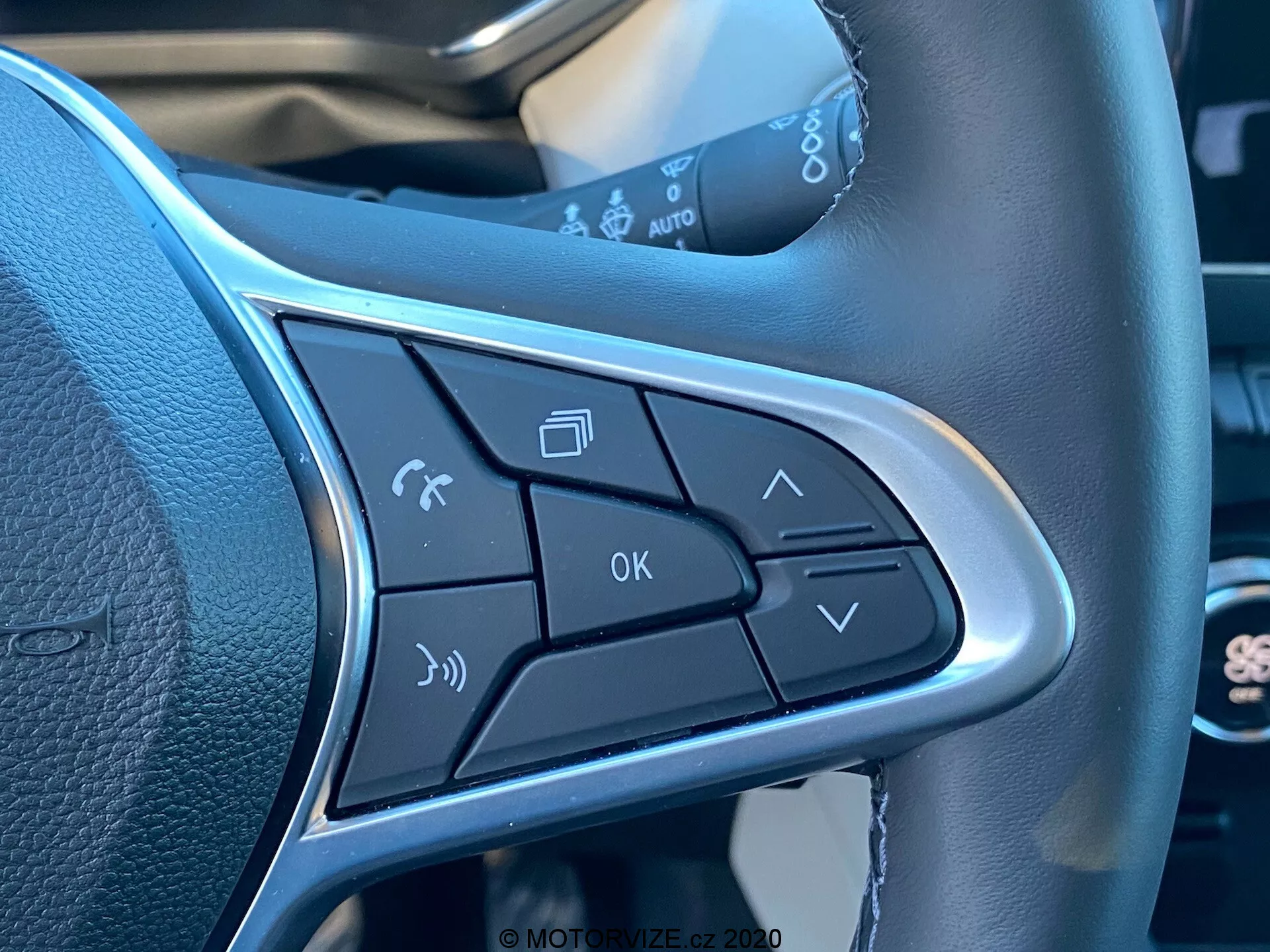 Vista ravvicinata dei pulsanti di controllo sul raggio del volante della Renault Captur 2020. Funzioni includono l'attivazione dei comandi vocali, la gestione delle chiamate, i controlli del volume, il pulsante OK e le frecce di navigazione dei menu. Il design elegante include un bordo argento che evidenzia i pulsanti, evidenziando il funzionamento a mani libere e la comodità.