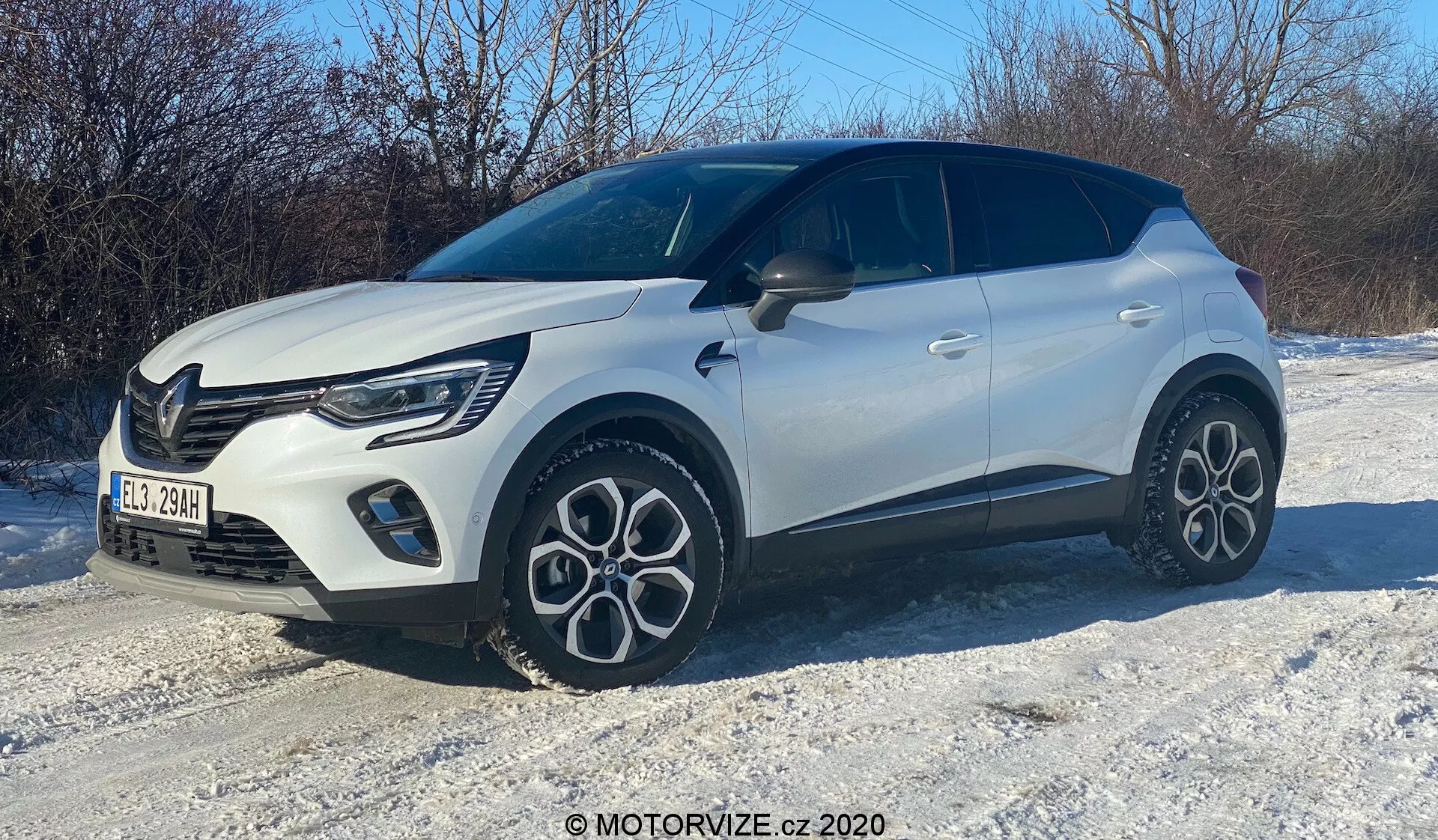 Immagine di un SUV compatto bianco su un terreno innevato, catturata da un angolo frontale di tre quarti. Il lato destro, il cofano, la griglia, i fari LED eleganti, la ruota anteriore e il parafango, la portiera del passeggero e una parte della sezione posteriore sono visibili. Il veicolo presenta un design moderno con linee audaci, distintivi cerchi in lega multirazze, colore della carrozzeria bicolore con tetto nero e un motivo distintivo della griglia con luci diurne visibili.