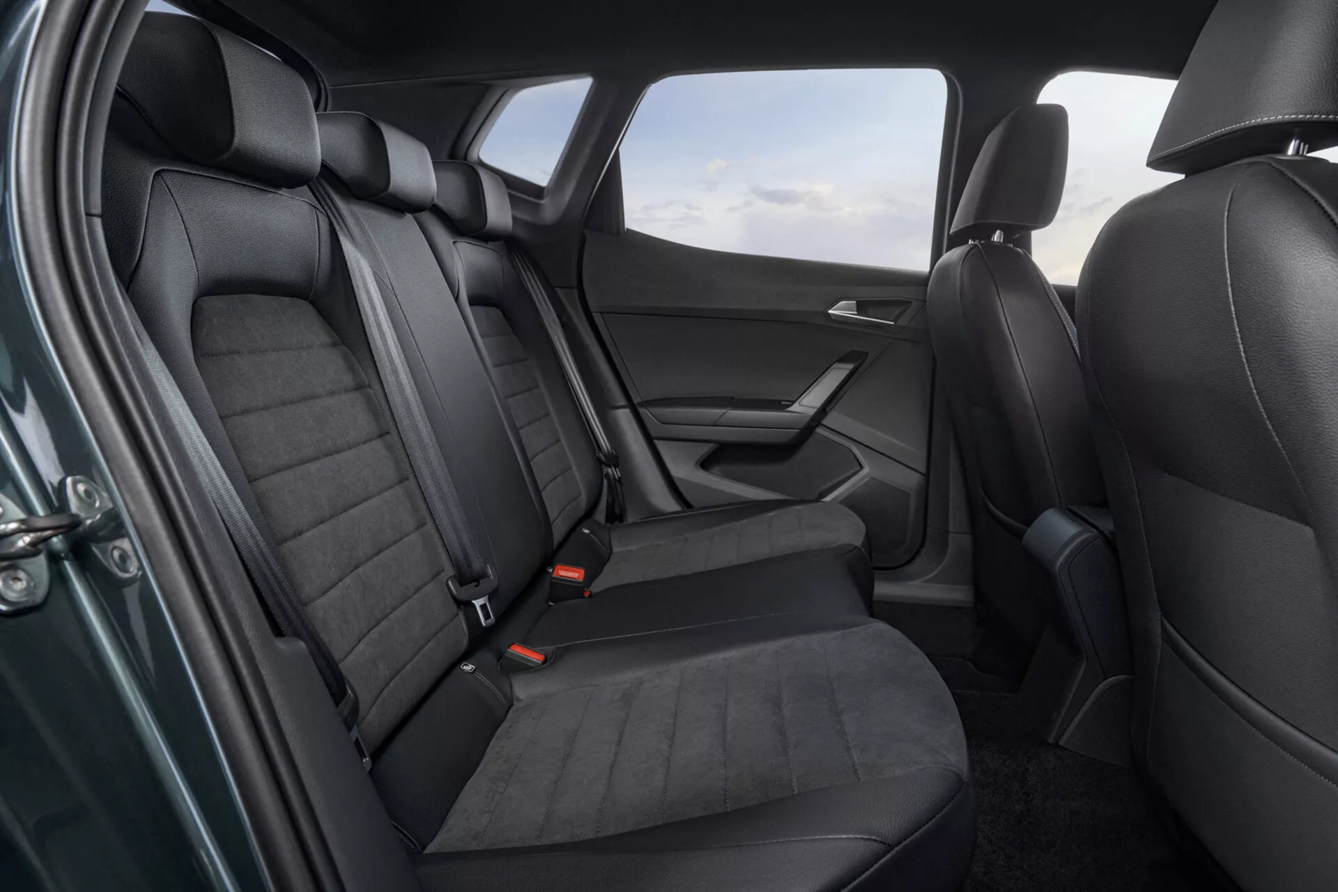 Scatto interno di un Seat Arona 2017 che mostra l'area dei sedili posteriori con vista dettagliata dei sedili rivestiti in pelle, pannello della porta e caratteristiche di sicurezza da un angolo rialzato