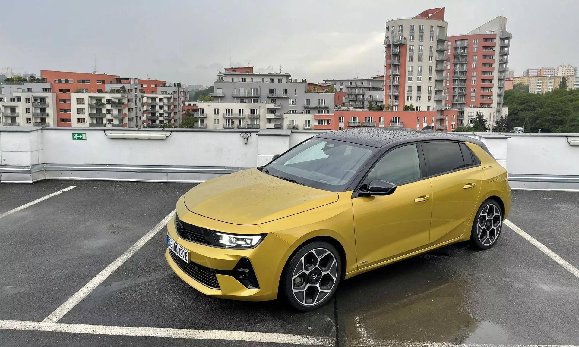 Hatchback Seat Arona 2017 in giallo vivace con tetto nero a contrasto, parcheggiata in una struttura a più piani, mostra fari LED sottili, griglia prominente con sensori avanzati, cerchi in lega sportivi a più razze e finestre oscurate in condizioni nuvolose e piovose