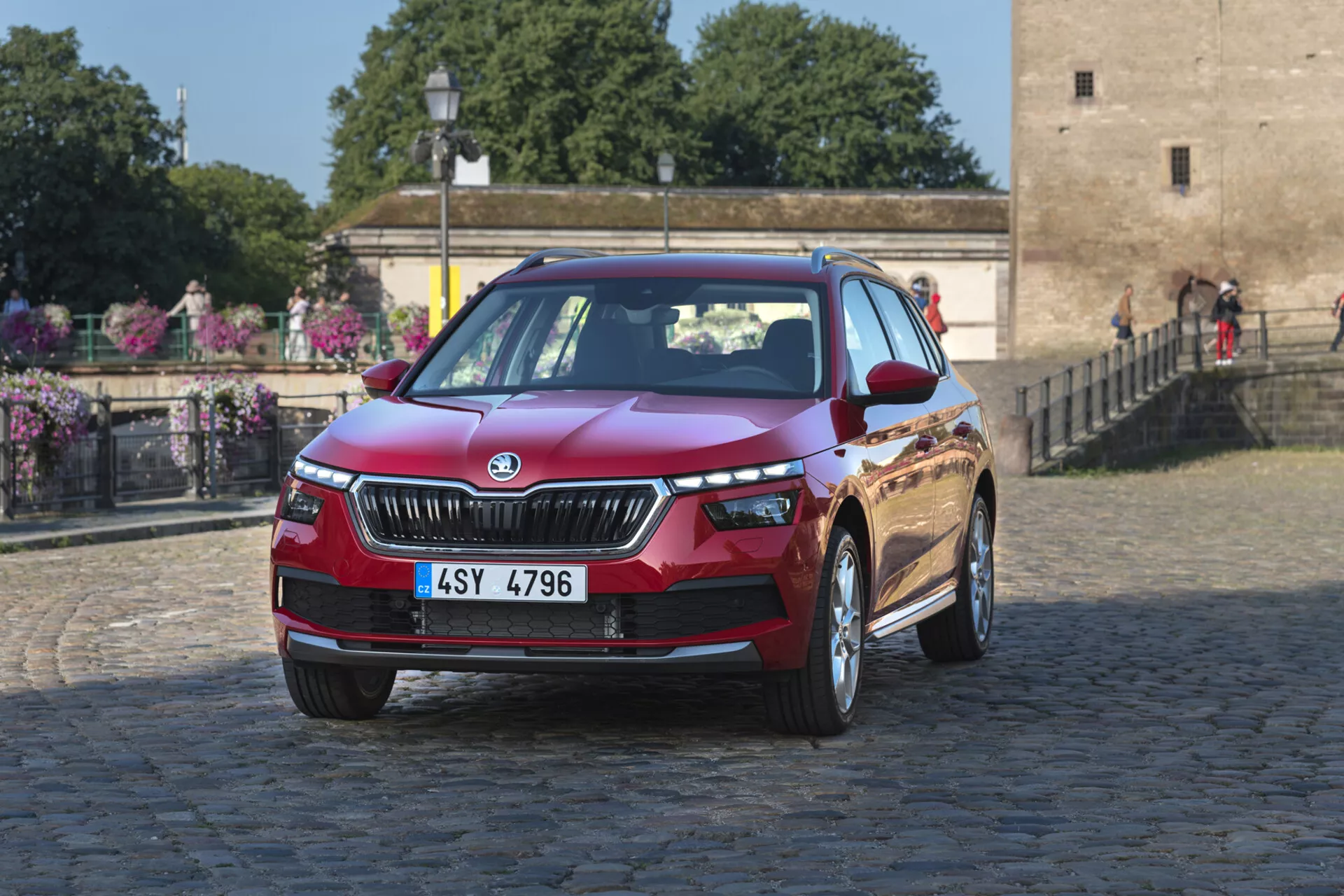 Skoda Kamiq del 2019 in rosso metallico profondo, che mette in mostra caratteristiche di design come la griglia, i fari LED e le ruote in lega su uno sfondo urbano di ciottoli