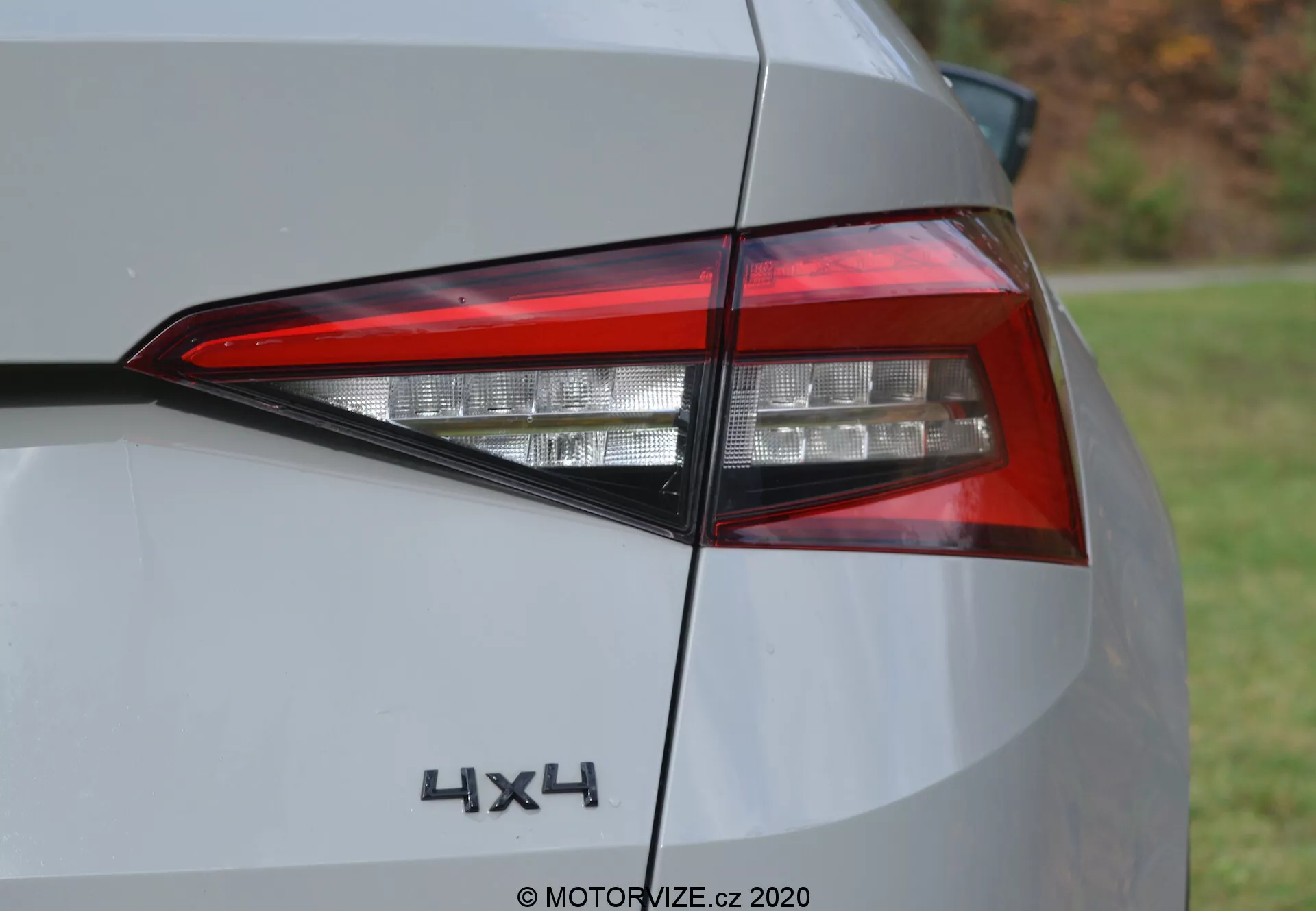 Vista ravvicinata della sezione posteriore di una Skoda Kodiaq 2017, evidenziando l'assemblaggio delle luci posteriori a LED contemporanee e il distintivo '4x4'. Lo scatto angolato mostra gli strati intricati degli elementi di illuminazione, il design angolare e una parte del pannello posteriore in colore argento o grigio chiaro. Foto diurna con luce naturale.