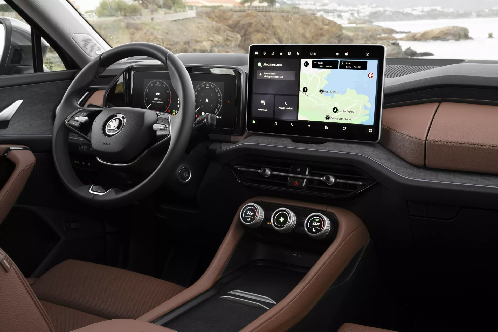 Primo piano dell'interno della Skoda Kodiaq 2024 che mostra il cruscotto e le funzionalità tecnologiche dalla prospettiva del conducente, includendo un quadro strumenti digitale, sistema di infotainment touchscreen con navigazione, tappezzeria di lusso bicolore, illuminazione ambientale e opzioni di connettività moderne