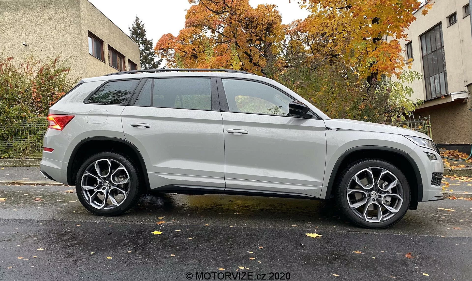 Profilo laterale di un SUV Skoda Kodiaq 2017 argento catturato da un leggero angolo, che evidenzia la ruota anteriore e il parafango. Mostra la lunghezza del veicolo e elementi di design come fari moderni, cerchi in lega multirazza, linea caratteristica prominente, barre sul tetto e fanali posteriori eleganti. Sfondo neutro con illuminazione uniforme. Credito fotografico: MOTORVIZE.cz 2020.