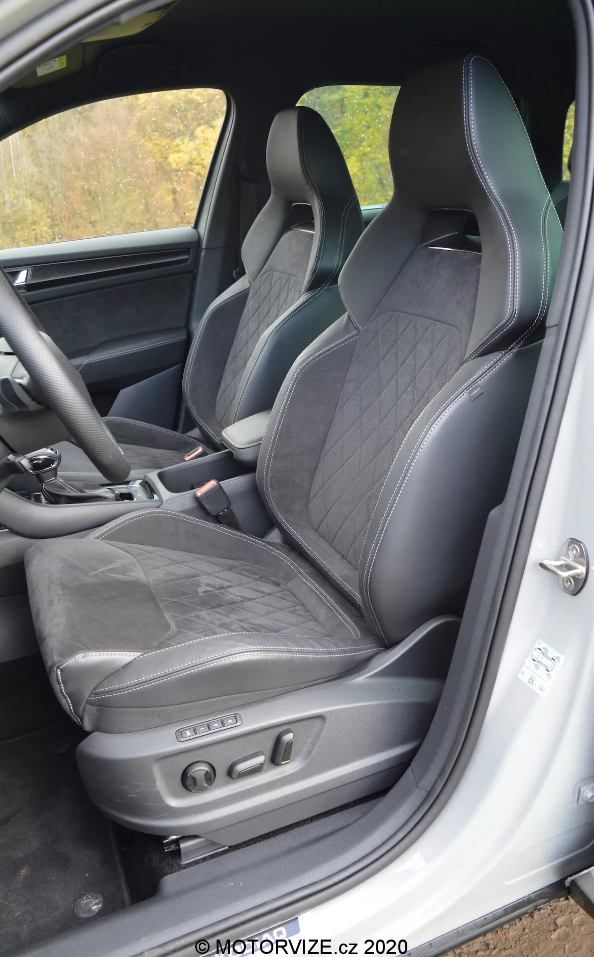 Vista interna di una Skoda Kodiaq 2017 concentrata sul sedile del conducente e sull'area circostante, con rivestimento in pelle nera con cuciture a diamante, poggiatesta integrato, supporto laterale per guida dinamica e regolazioni elettroniche del sedile con pulsanti di controllo. Le caratteristiche visibili includono il telaio inferiore della porta con soglia e un'unità altoparlante, indicativi di un interno lussuoso e sportivo con tecnologia avanzata dei sedili.