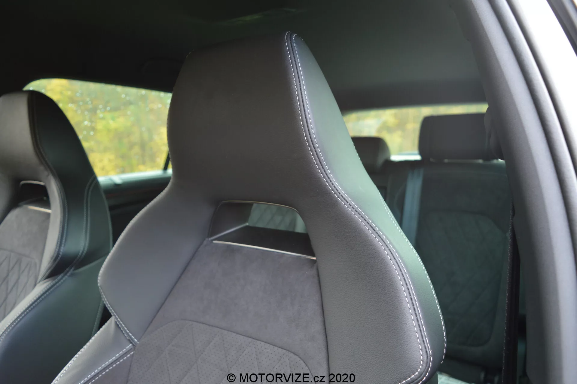Interno di una Škoda Kodiaq 2017, con attenzione al sedile anteriore del conducente da una prospettiva posteriore laterale, evidenziando l'imbottitura in pelle e tessuto testurizzato con cuciture precise sui bordi. Il sedile dal design moderno e sportivo presenta pronunciati supporti laterali per un maggiore supporto, poggiatesta integrato e motivo a trapuntatura diamante che suggerisce un'estetica premium. Lo sfondo degli interni è leggermente sfocato per enfatizzare il sedile.