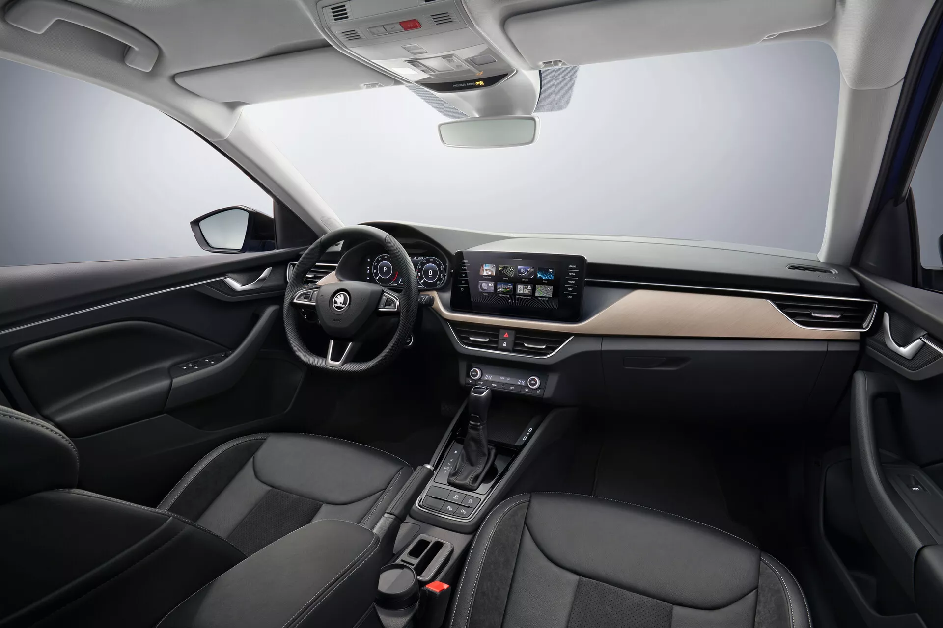 Vista interna Skoda Scala 2019 che mostra le aree guidatore e passeggero, dotata di volante a sinistra con comandi integrati, cruscotto moderno con accenti in metallo spazzolato, cluster strumenti digitale dietro al volante, sistema di infotainment con schermo touchscreen da 8 pollici, console centrale minimalista con selettore di marcia automatico, sedili in pelle nera accentata e tecnologia avanzata del veicolo che include controllo automatico del clima e funzionalità di connettività, sotto un'illuminazione da studio soffice che mette in risalto l'ampio layout e il design ergonomico dell'auto.