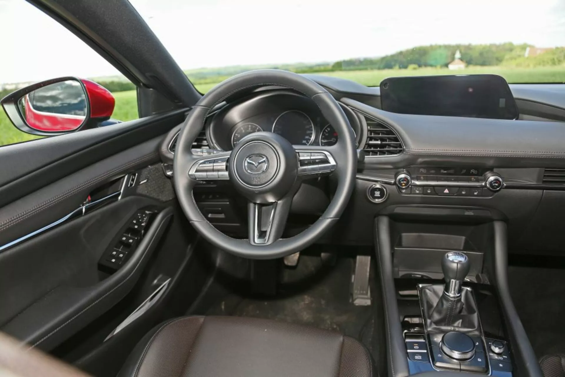 Vista interna della Skoda Scala 2019 con focus sul lato guidatore con sedile passeggero in pelle, leva del cambio manuale, cruscotto elegante con sistema di infotainment e volante multifunzione