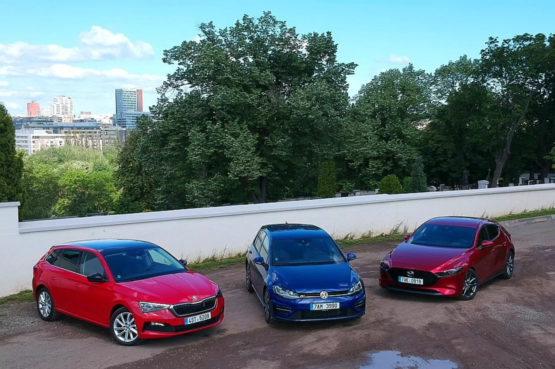 Skoda Scala hatchback del 2019 parcheggiate affiancate in un contesto urbano, che mostrano i colori rosso, blu e bordeaux con una ripresa ad angolo alto da una posizione elevata, evidenziando le loro ruote in lega, fari alogeni e design aerodinamici