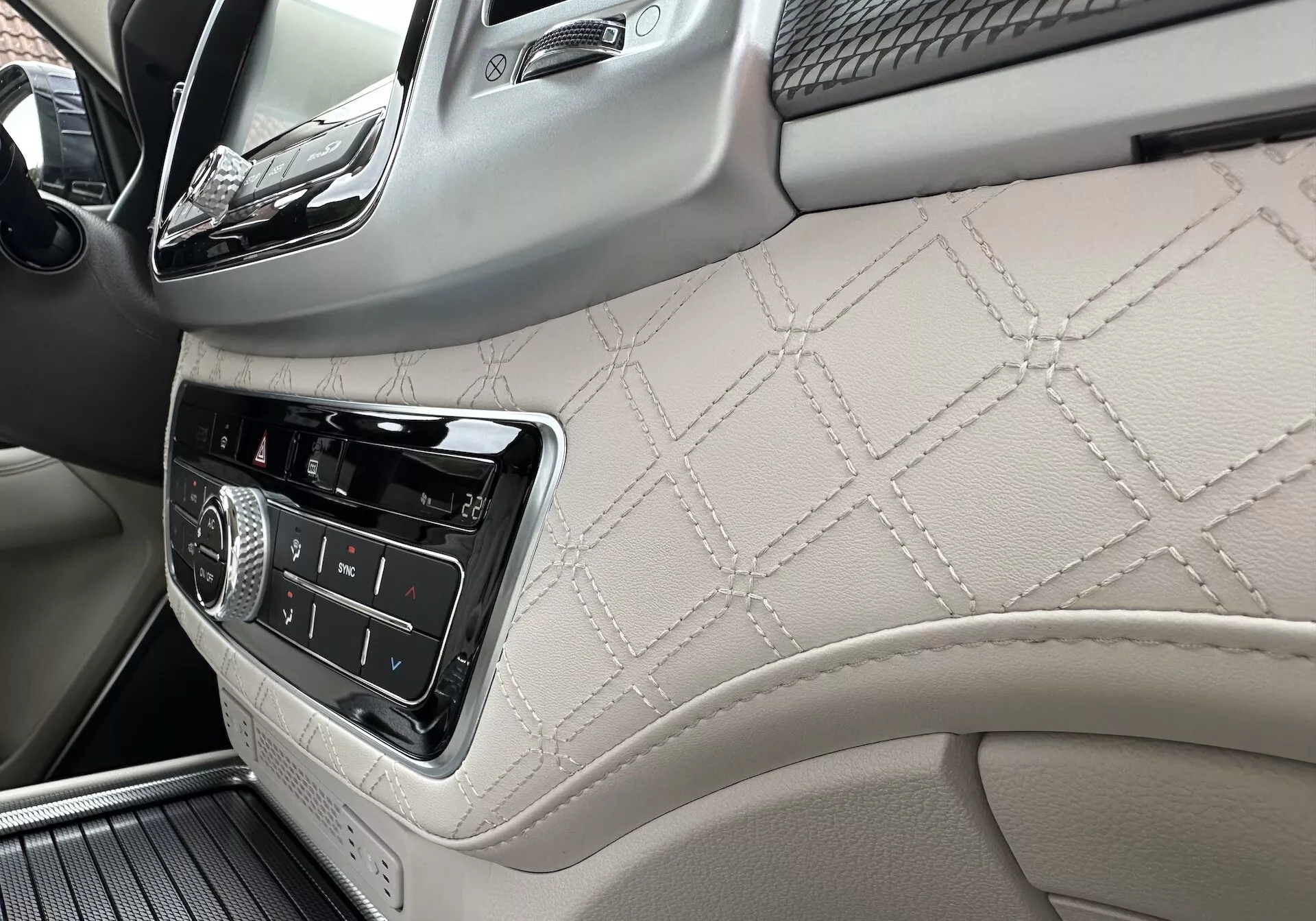 Interni SsangYong Rexton 2021 con focus sul lato passeggero della plancia e parte del pannello della porta anteriore con pelle trapuntata a diamante, controlli dell'infotainment e dettagli in legno di lusso