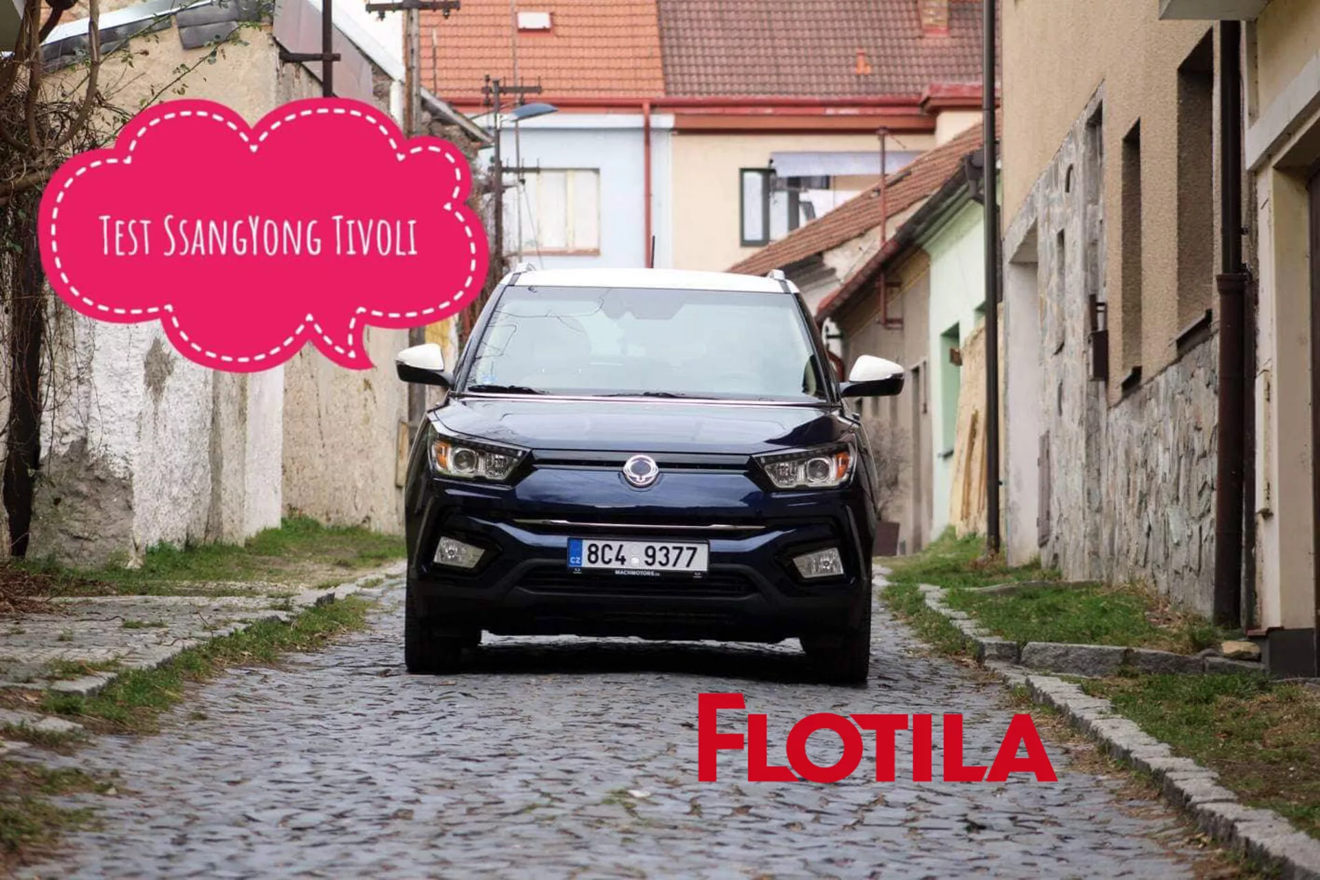 Vista frontale di un modello SsangYong Tivoli 2019 posizionato in una stretta strada europea lastricata mostra la moderna griglia del veicolo, i fari LED e il design contemporaneo del SUV compatto, con una grafica a fumetto che oscura parzialmente la parte superiore centrale dell'immagine.