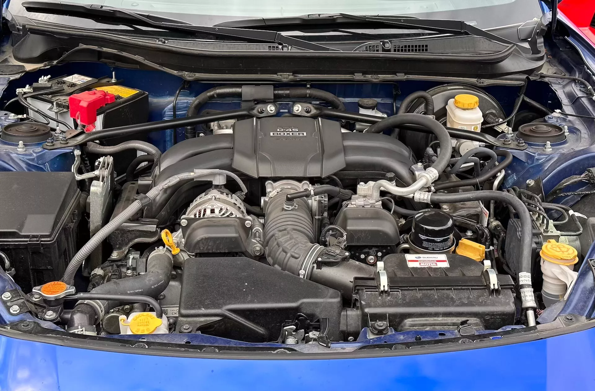Vista dettagliata del vano motore della Subaru BRZ 2023 con motore BOXER, batteria, serbatoi dei fluidi e sistema di aspirazione aria visibili