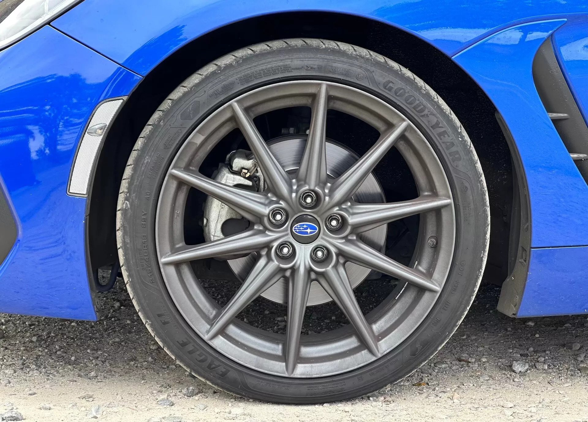 Immagine ravvicinata della Subaru BRZ 2023 che mostra la ruota in lega anteriore e il pneumatico Continental, con la carrozzeria blu vibrante visibile