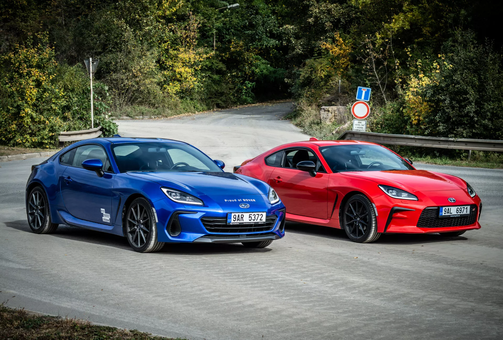 Coupé sportive Subaru BRZ 2023 in blu e rosso con design aerodinamico e caratteristiche di performance, parcheggiate all'aperto circondate da fogliame naturale
