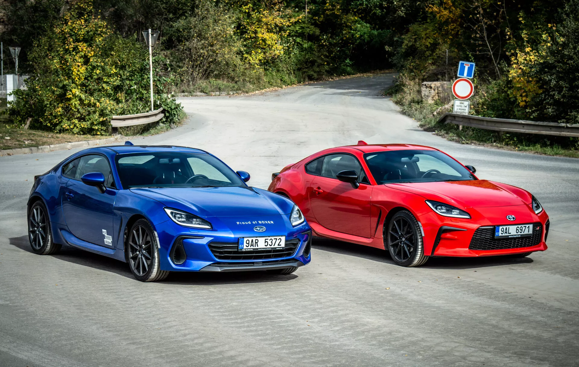 Duo di Subaru BRZ 2023 che mostrano auto sportive stile coupé in blu vibrante e rosso accattivante parcheggiate fianco a fianco sull'asfalto con elementi di design aerodinamico, fari LED moderni e ruote orientate alle prestazioni sotto la luce naturale del giorno