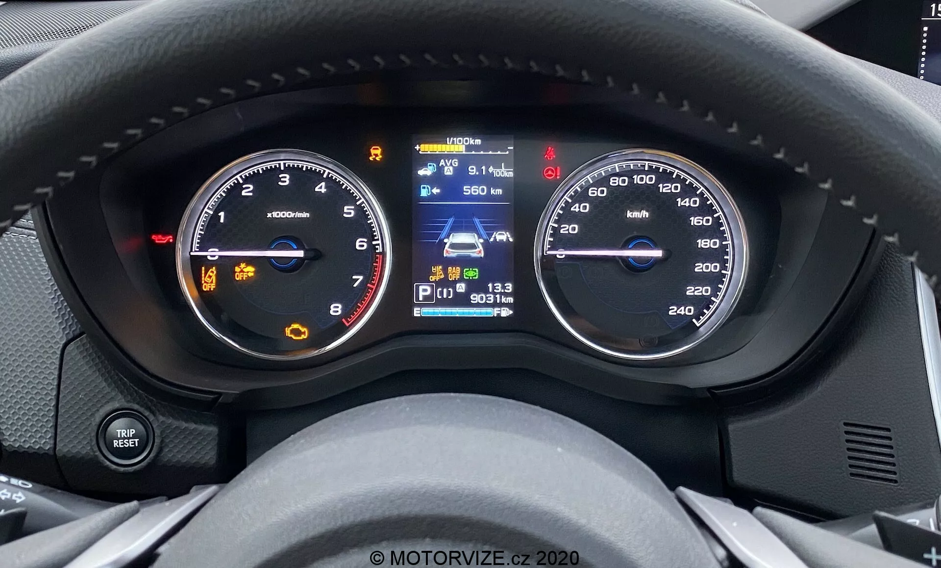 Vista interna ravvicinata del quadro strumenti del Subaru Forester 2020 dalla prospettiva del conducente, che mostra un contagiri analogico con la lancetta ferma sopra gli 0 giri/min, display digitale con mappa di navigazione, indicatore del carburante pieno e funzioni di assistenza alla guida, insieme a un tachimetro analogico tarato fino a 260 km/h, indicando che il veicolo è inattivo. Design moderno con display digitali integrati.