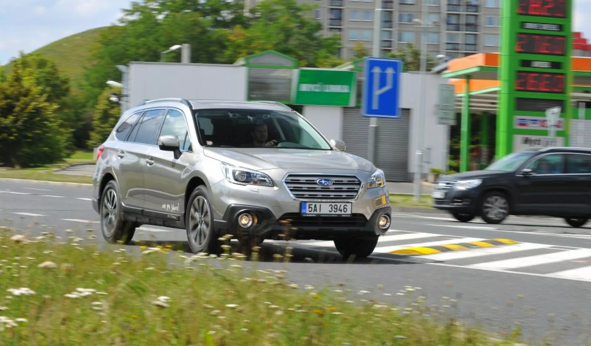 Subaru Outback del 2003 in movimento, mostrando una vista frontale di tre quarti con griglia dettagliata, fari e ruote, evidenziando il suo design da SUV compatto e caratteristiche utili come le barre sul tetto, in condizioni di sole.