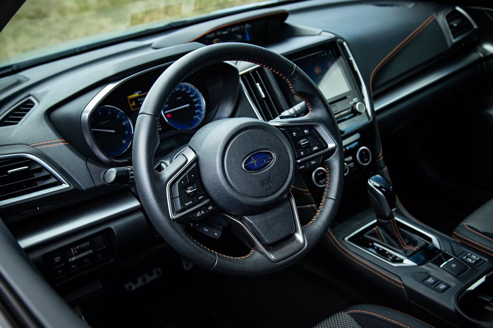 Vista interna della Subaru XV 2021 dalla prospettiva del guidatore con volante centrale rivestito in pelle con comandi montati, cruscotto analogico e digitale, sistema di infotainment touchscreen e trasmissione automatica