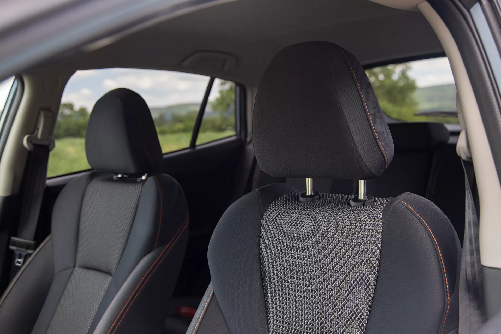 Vista interna della Subaru XV 2021 con sedili in pelle nera con inserti in tessuto a motivo e cuciture arancioni distintive, concentrata su comfort e design dalla prospettiva di un passeggero posteriore
