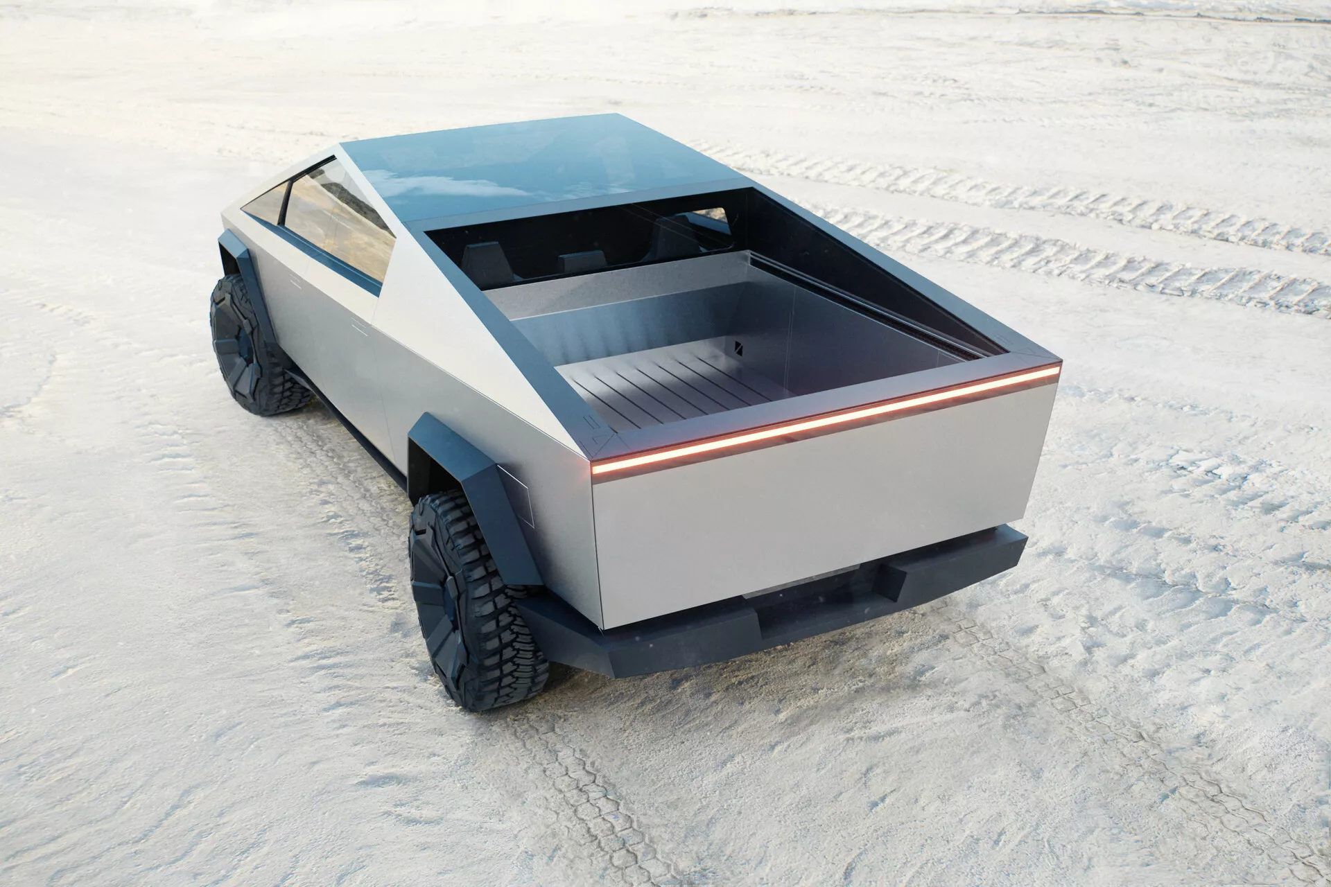 Futuristico e unico Tesla Cybertruck 2021, prima generazione, catturato da un'alta angolazione posteriore. La vista include il letto posteriore del veicolo, parte del suo profilo laterale e il tetto piatto. Il letto posteriore è poco profondo con una superficie piatta, delineato da una striscia luminosa continua, evidenziando un design moderno. I pannelli laterali mancano di stile convenzionale, mostrando un approccio minimalista. Gli pneumatici grandi e all-terrain suggeriscono una capacità fuoristrada. L'assenza di specchietti tradizionali e prese di scarico suggerisce una possibile alimentazione elettrica. Il camion è posizionato su una superficie piana e testurizzata che sembra una distesa di sale.