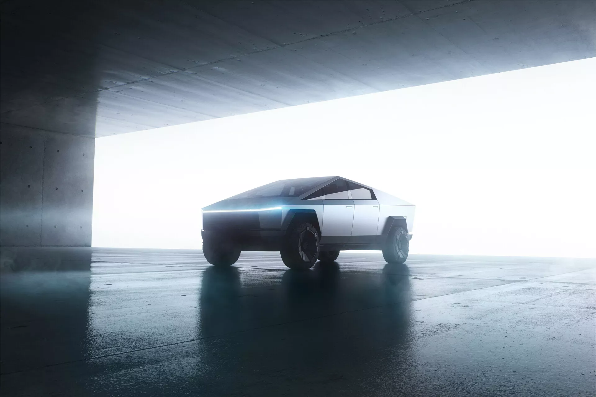 Vista laterale del Tesla Cybertruck 2021 in un parcheggio. Il veicolo, dal design futuristico e angolare, è leggermente inclinato verso la telecamera, mostrando le sue linee geometriche minimaliste. L'illuminazione retrostante migliora la sua silhouette creando un effetto alone. Le superfici piatte e affilate dell'auto e le robuste ruote da fuoristrada suggeriscono una tecnologia di propulsione avanzata, probabilmente elettrica.