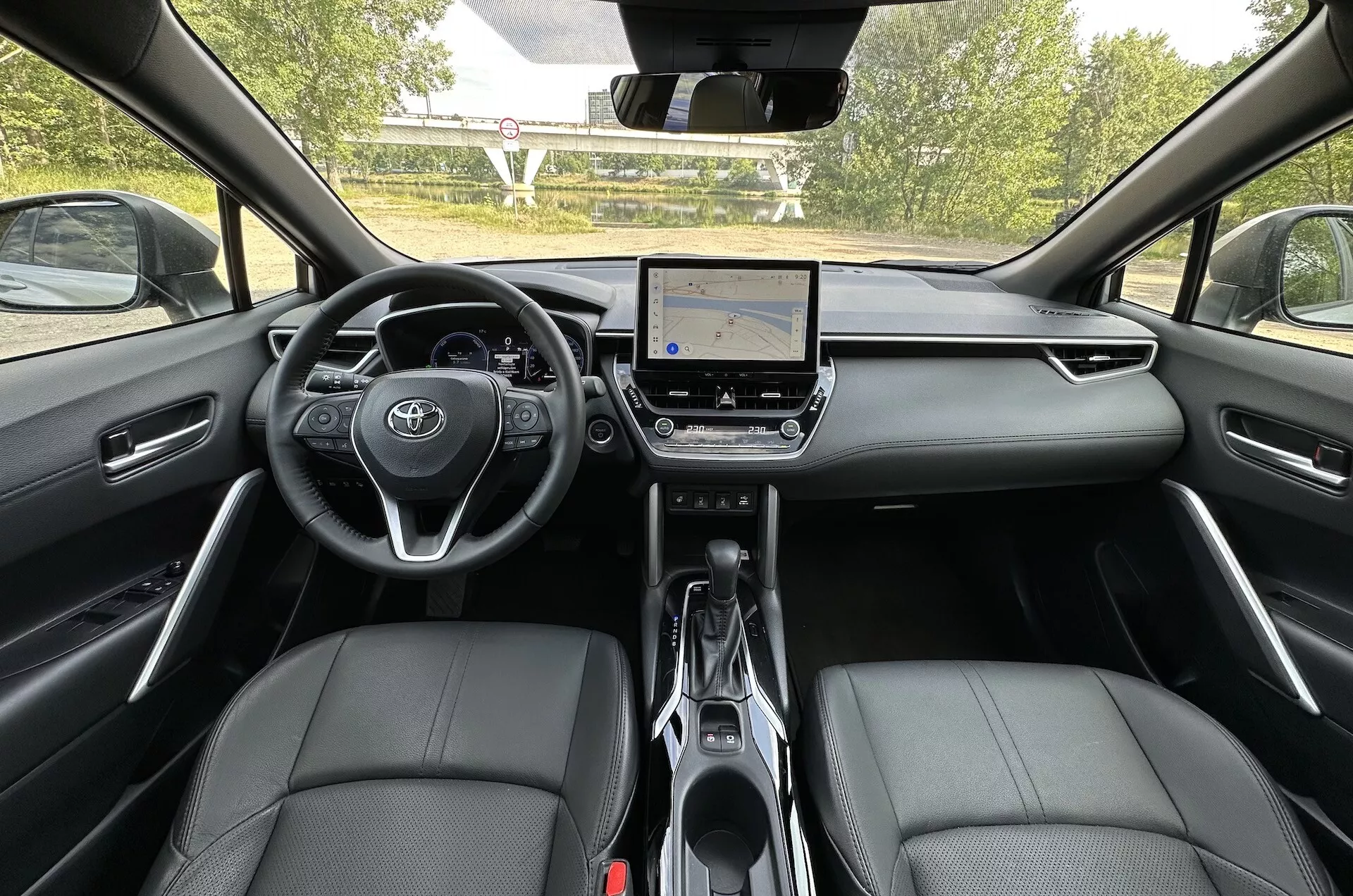 Vista interna della Toyota Corolla Cross 2022 dal sedile posteriore che mostra il cruscotto, il sistema di infotainment touchscreen e i sedili anteriori in pelle