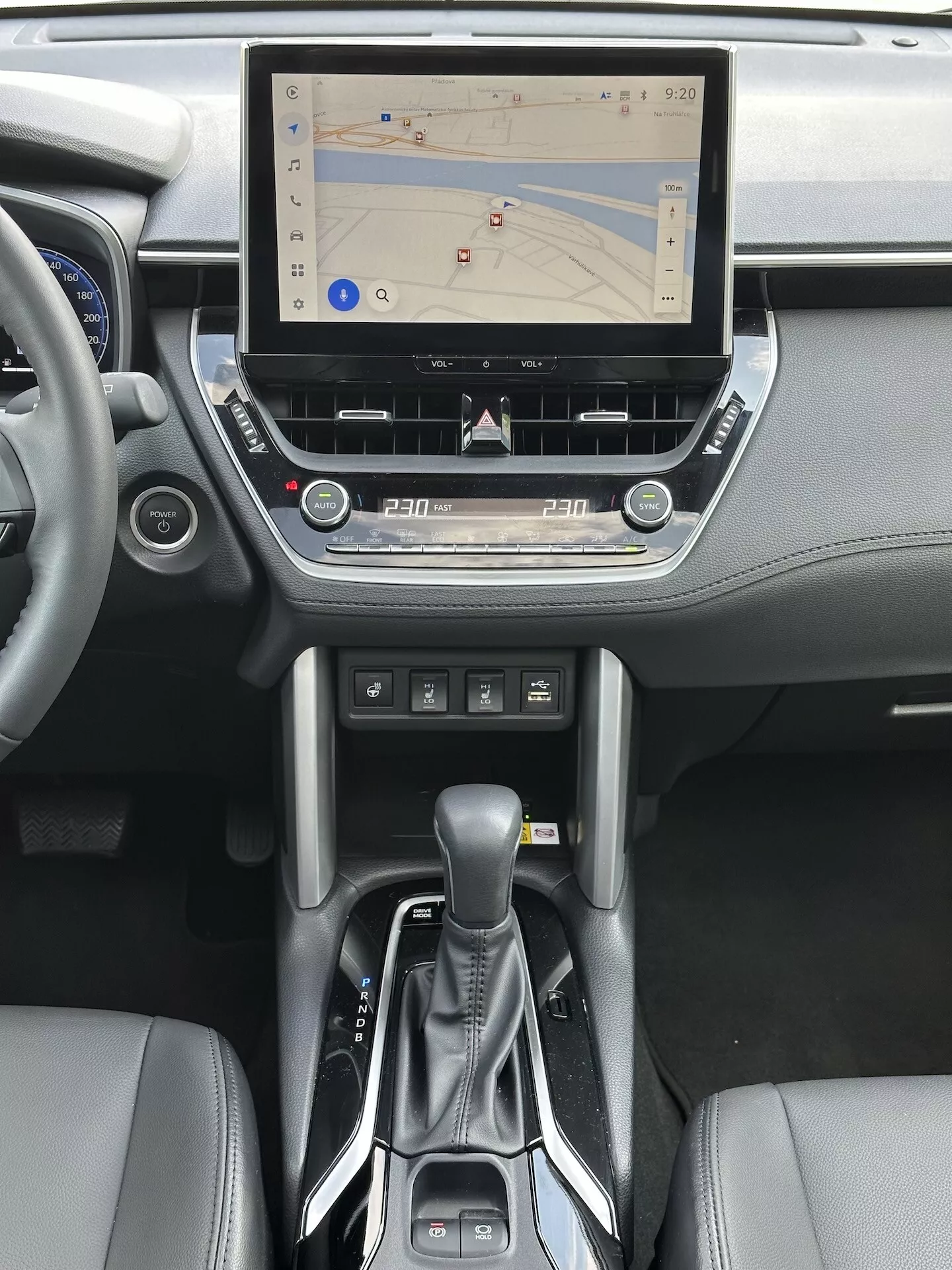 Interni Toyota Corolla Cross 2022 con sistema di infotainment touchscreen con navigazione GPS, controllo clima bizona, lettore CD, pulsanti di controllo media e telefono, leva del cambio automatica moderna e accenti in pelle nella consolle centrale e design del cruscotto