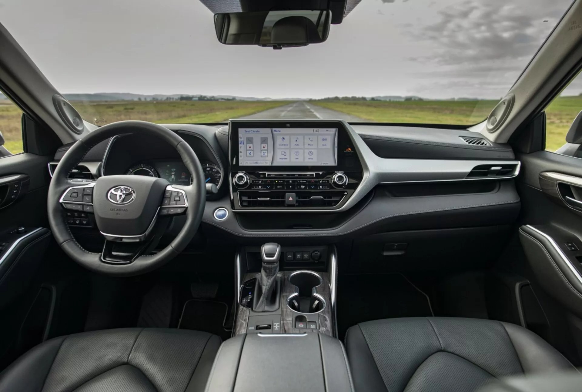 Panoramica dell'interno di Toyota Highlander 2021 che mostra cruscotto, quadro strumenti digitale, display del sistema di infotainment e sedili anteriori rivestiti in pelle dalla prospettiva dei sedili posteriori