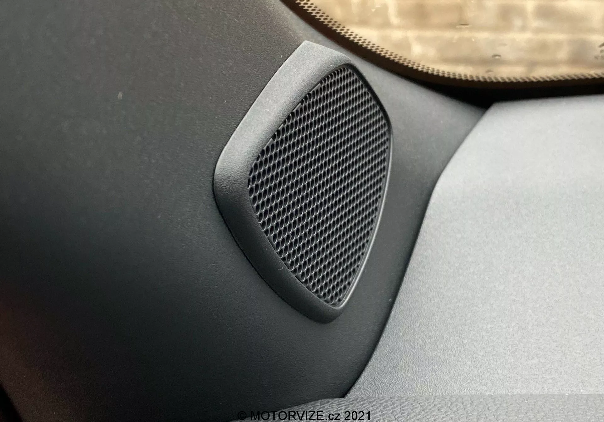 Vista ravvicinata di un altoparlante per auto sul pannello della portiera con motivo geometrico, integrato nel pannello in grigio scuro o nero, ripresa da un angolo elevato che mette in risalto la texture dell'altoparlante e la qualità audio in una Toyota Yaris 2020.