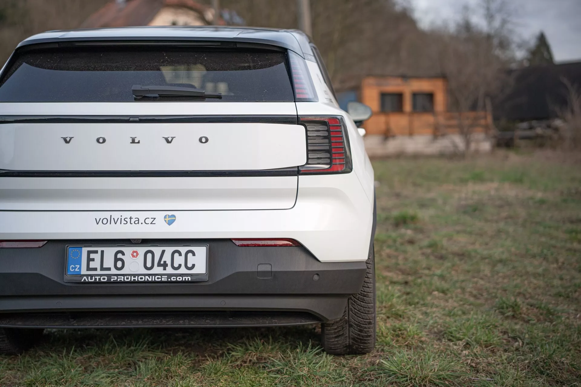 Vista posteriore di una Volvo EX30 2024 che evidenzia le uniche luci di coda verticali, il paraurti posteriore e l'area della targa su uno sfondo erboso